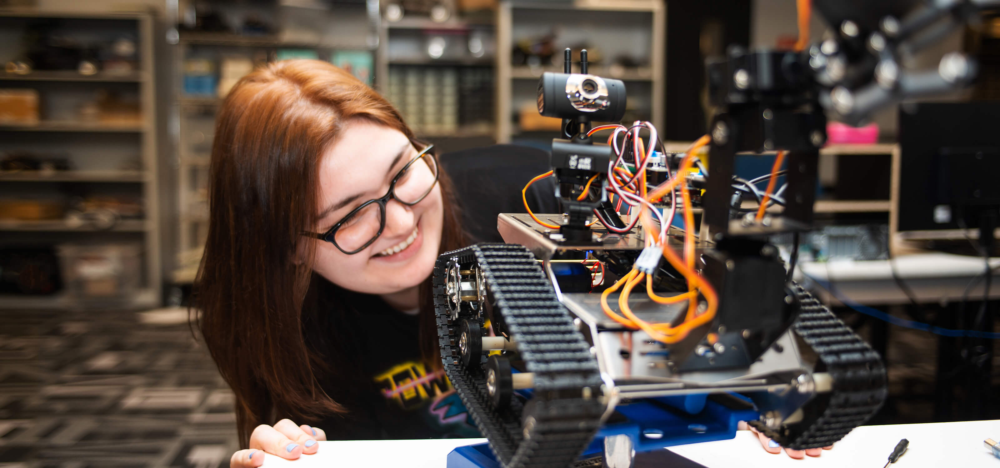 A DigiPen student smiles as she examines her robot