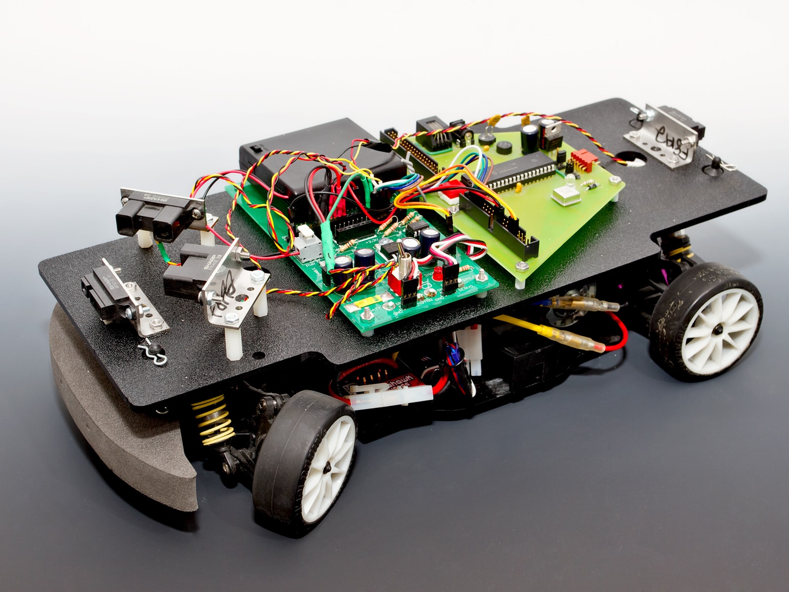 A four wheeled car with infrared sensors and exposed circuitry.