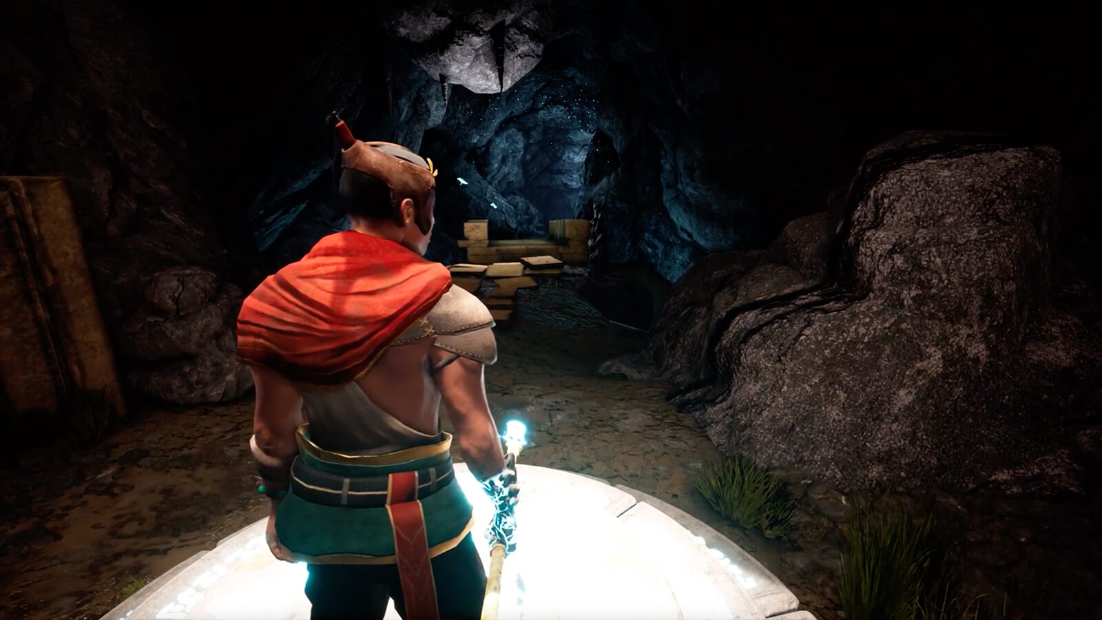 A man in a cavern holding a glowing spear.