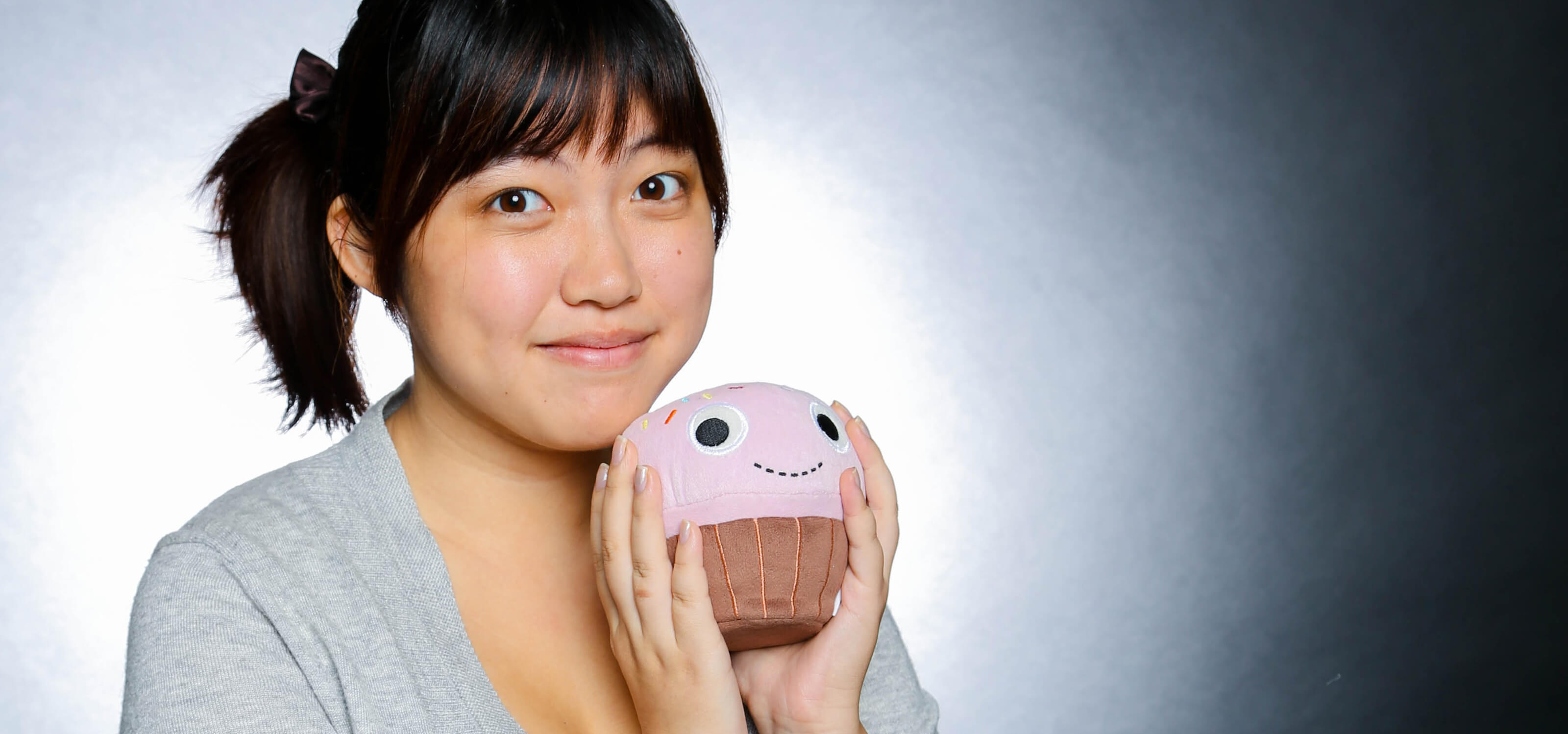 DigiPen alumna Jessica Nam posing with a cupcake-shaped plush toy