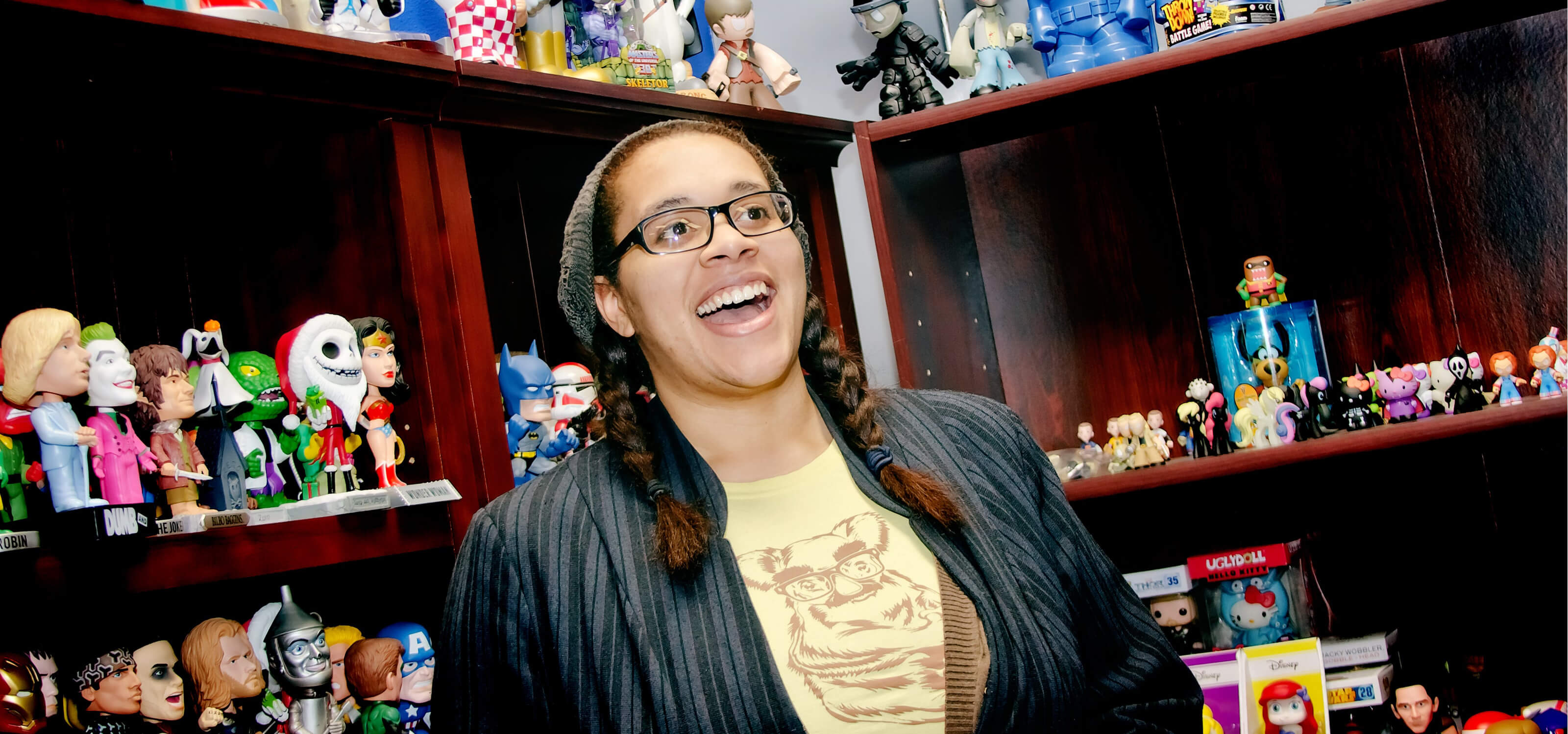 DigiPen BFA alumna Nnenna Ijiomah smiling in front of bookshelves filled with Funko figurines at the Funko office
