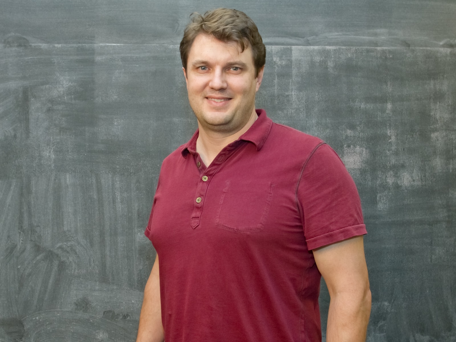 DigiPen physics professor Charles Duba smiling in front of a blackboard