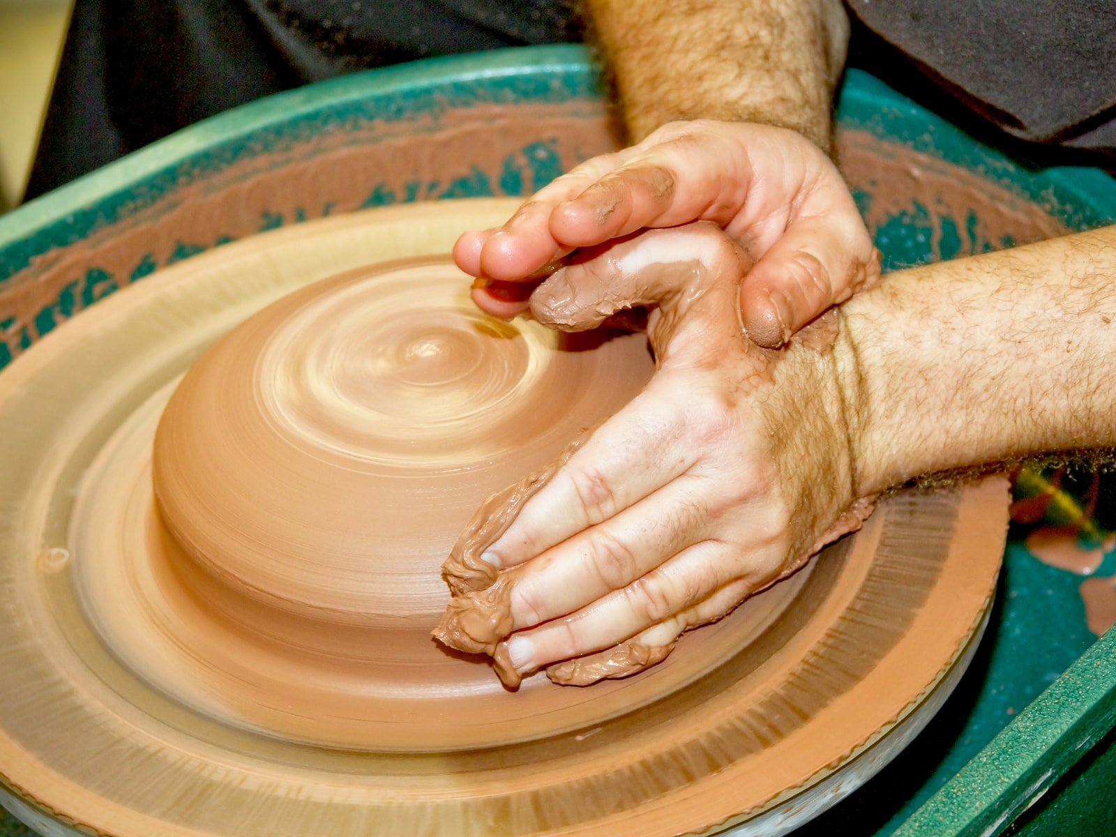 Hands molding clay on a spinning wheel in the new DigiPen ceramics studio