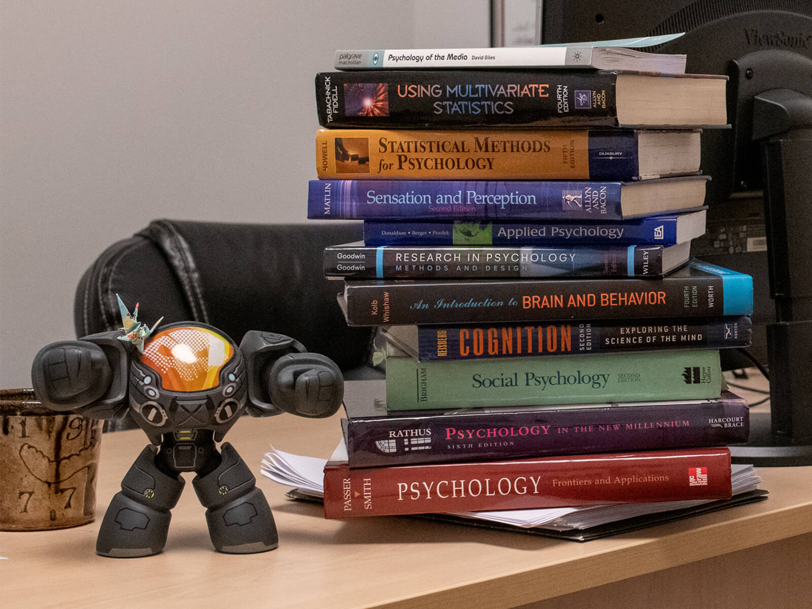 A stack of psychology textbooks sits atop a desk.