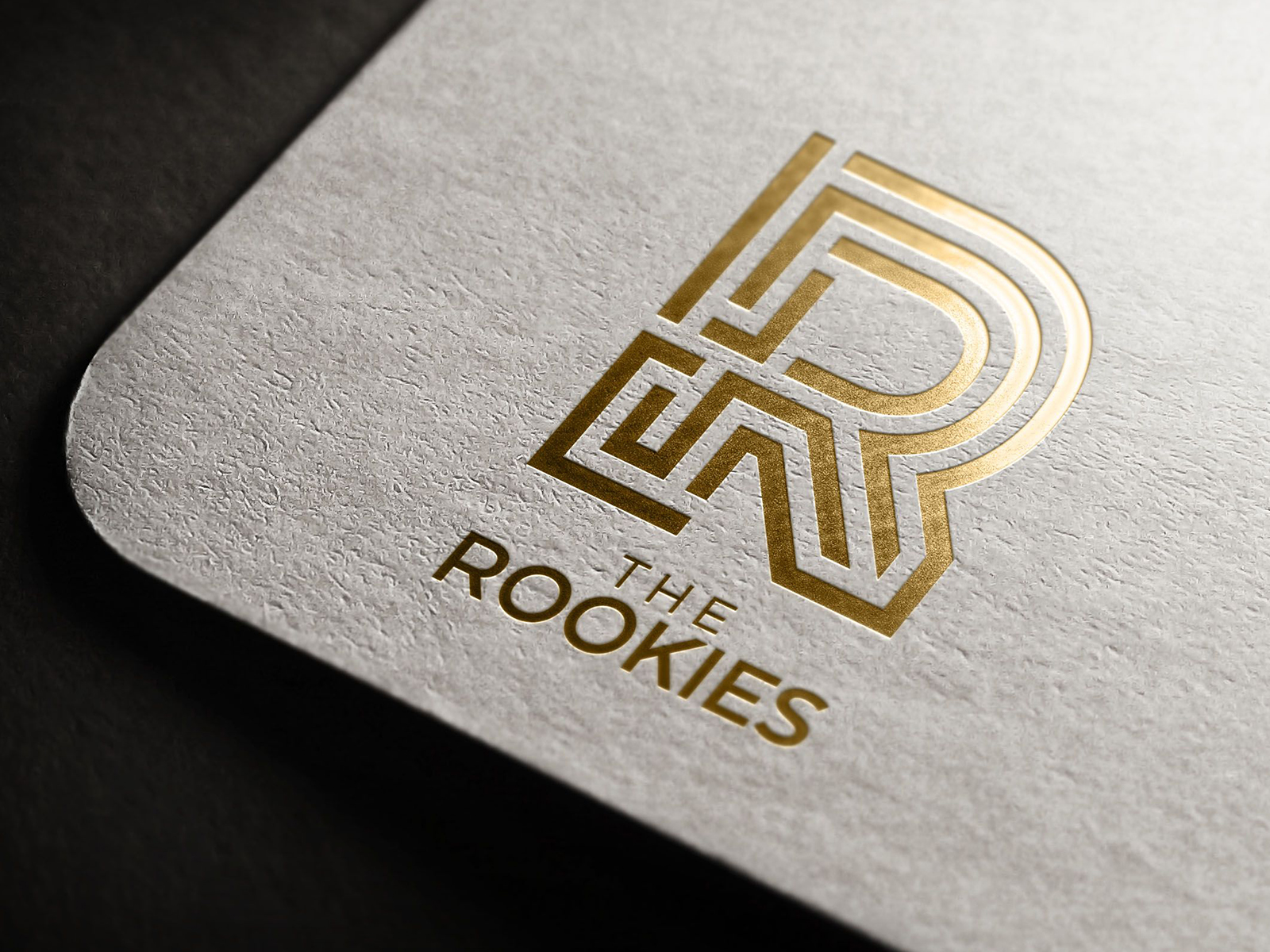 Golden "R" logo for the Rookies imposed near corner of grey paper