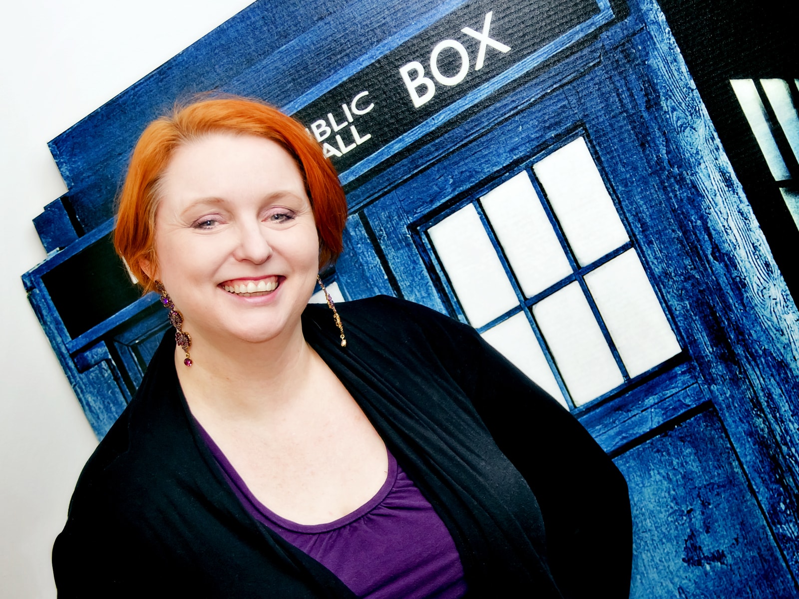 DigiPen lecturer Sonia Michaels smiling in front of the Dr. Who Tardis (a blue police box time machine) cutout in her office