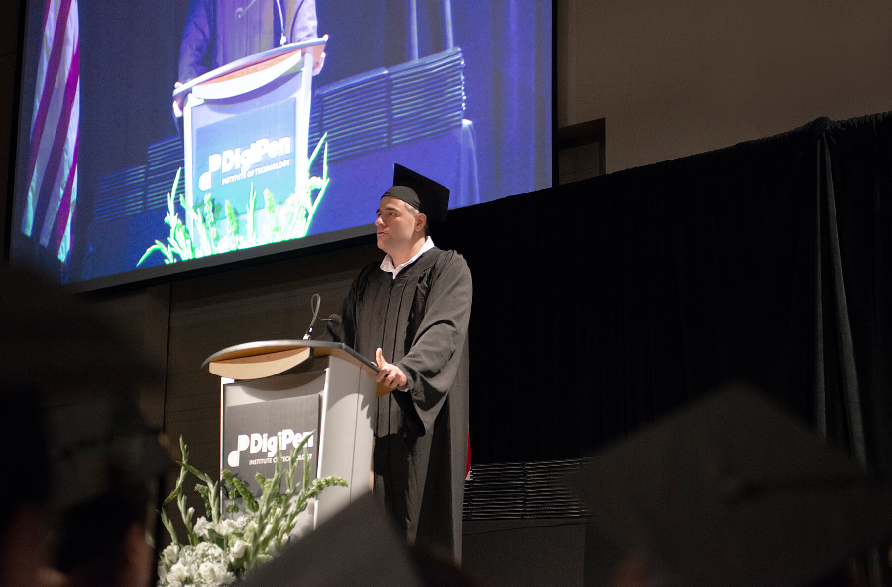 Anthony Saulls delivers a speech on stage at the 2018 DigiPen commencement ceremony.