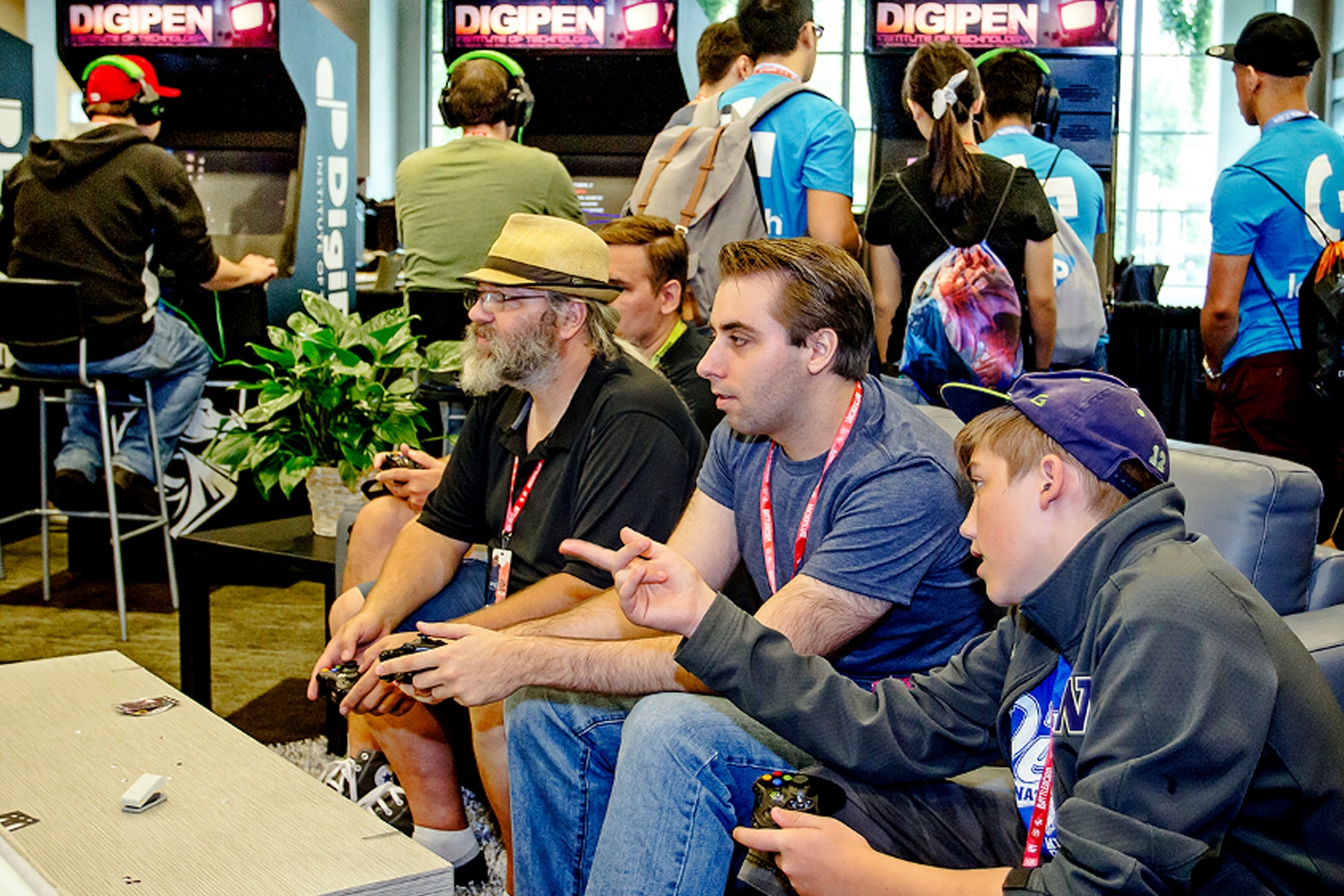 PAX attendees play games on a couch in the DigiPen arcade booth