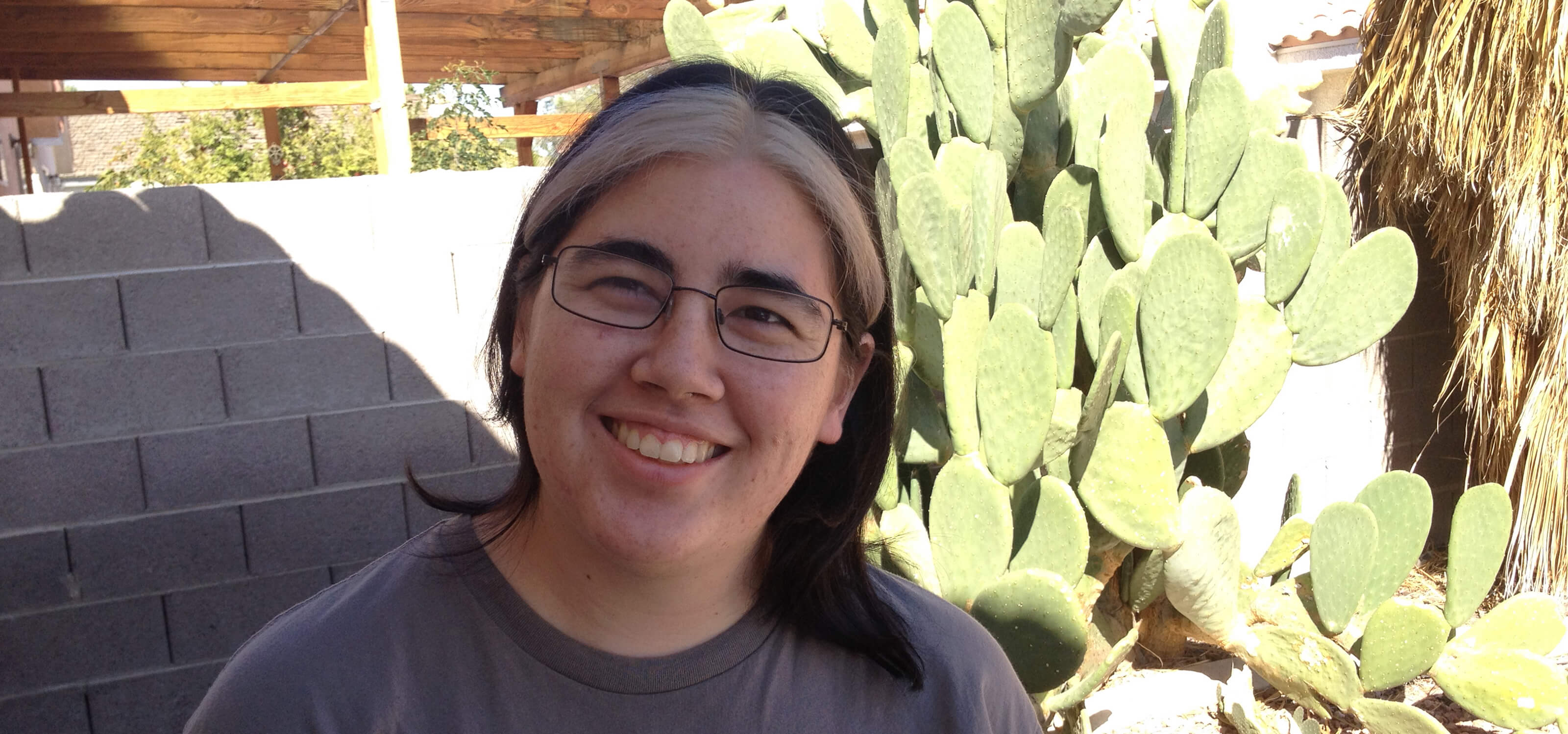 DigiPen graduate and Spry Fox senior software engineer Molly Jameson poses in front of a cactus. 