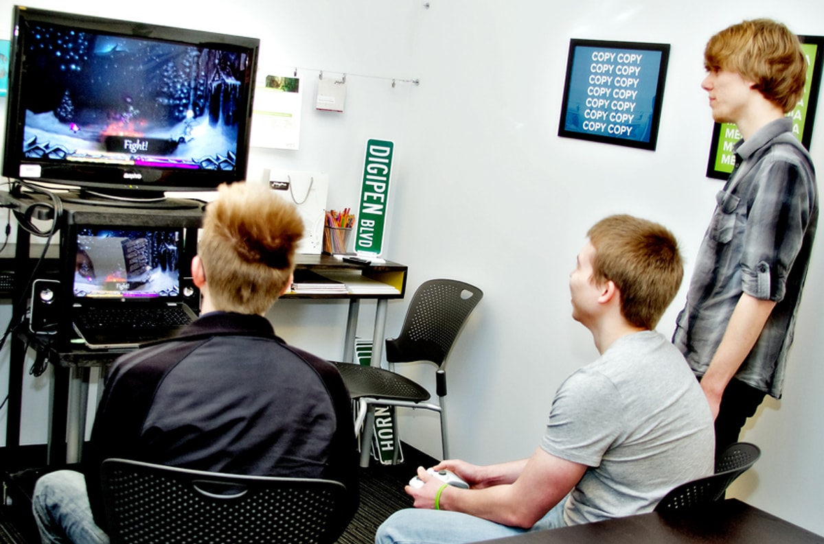 Two DigiPen students play Frozen Masquerade as Andrew Nack watches