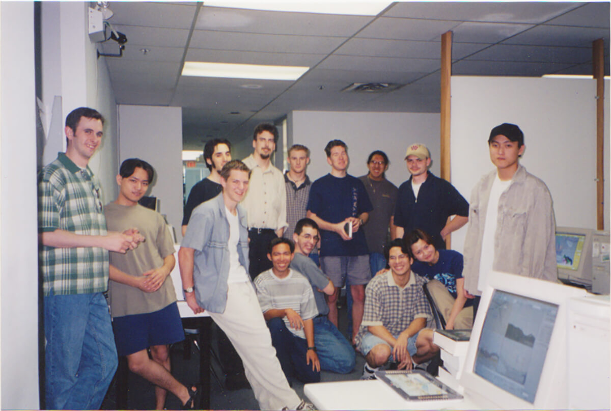 Duncan Shields poses with 13 fellow students in a computer lab at DigiPen Vancouver. 