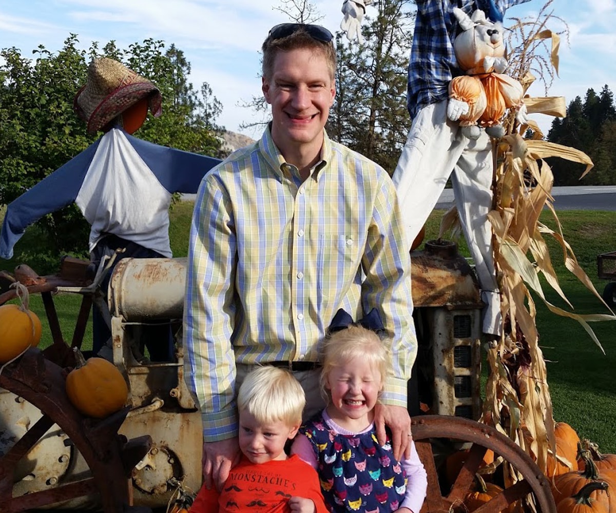 Erik Mohrmann and his two kids smiling at a pumpkin patch