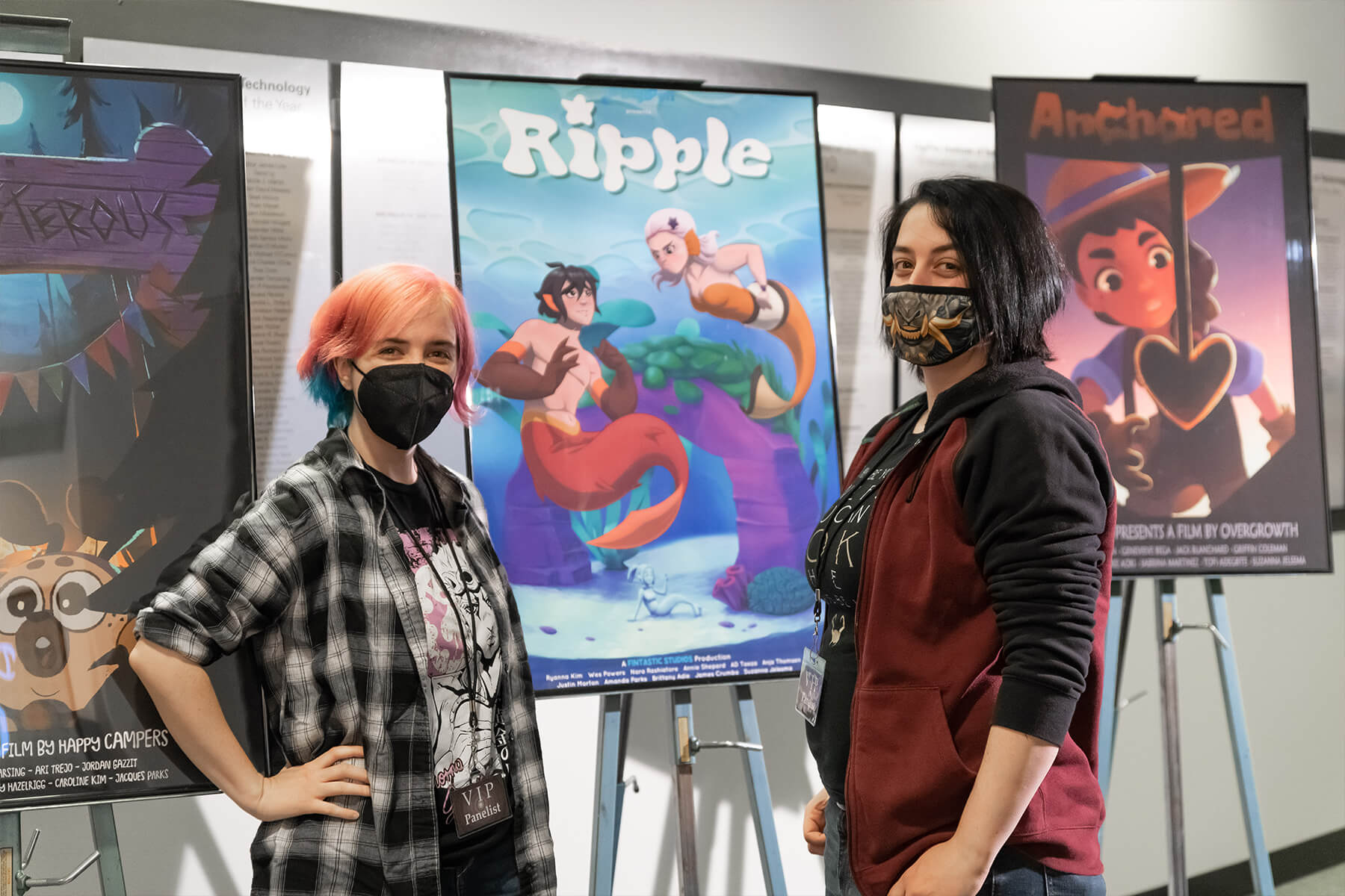 Two students pose in front of the DigiPen Film Festival poster for their film, Ripple.