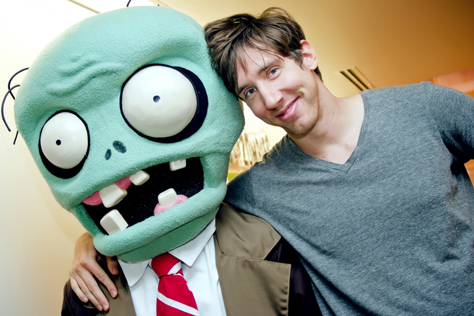 Mark Barrett smiling with his arm around the PopCap zombie mascot
