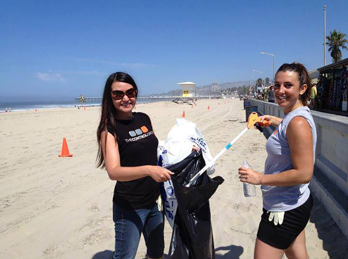 DigiPen graduate Romina Barrett volunteers with a fellow employee at The Control Group by collecting beach trash.