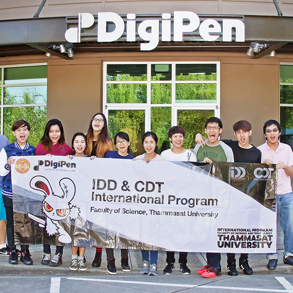 Students from Thammasat University in Thailand pose with a banner in front of DigiPen's main entrance