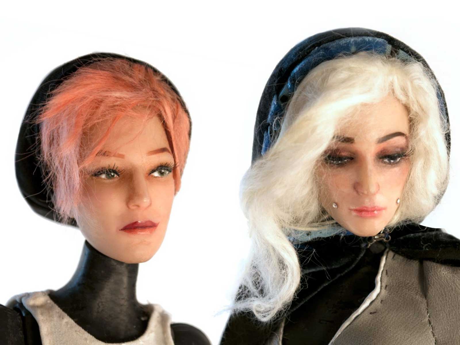 A head shot of two dolls side-by-side, one with short red hair and one with long white hair.