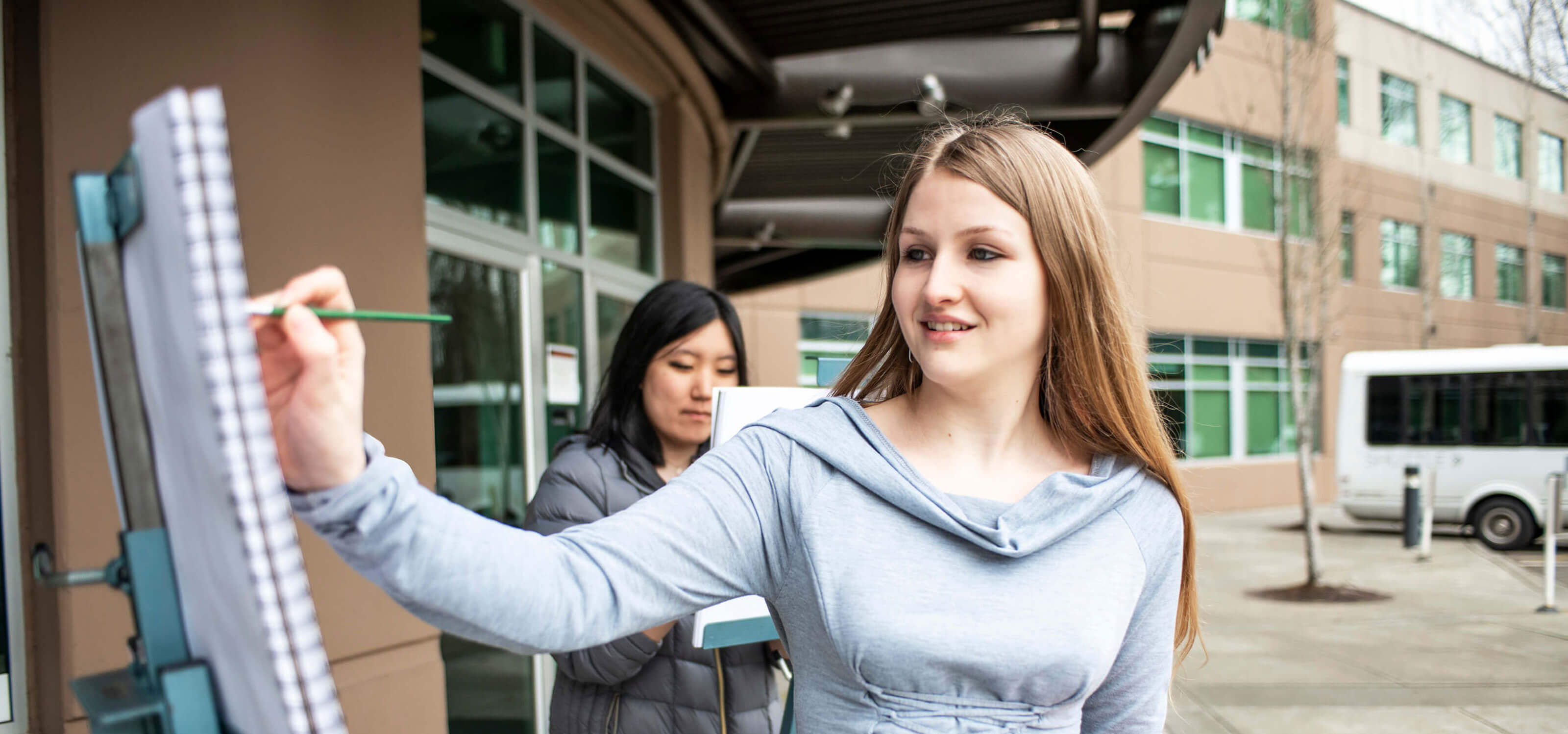 A DigiPen student painting on an easel outside the campus main entrance