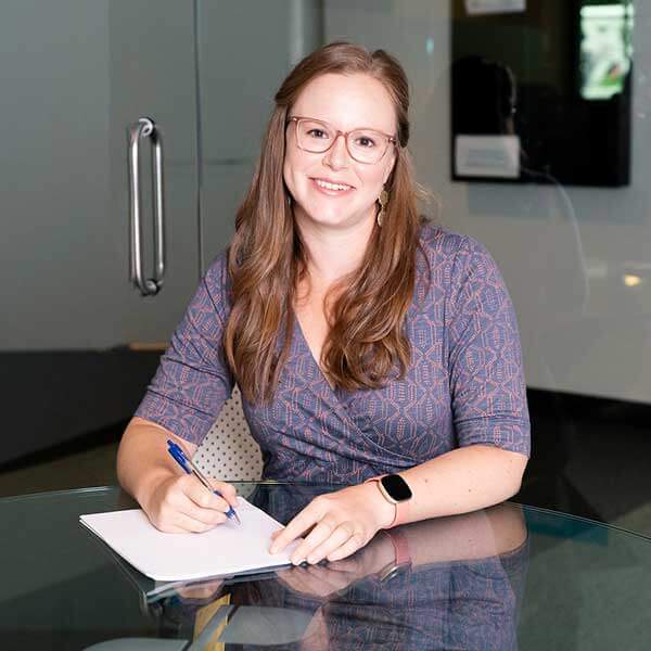 A DigiPen financial aid representative sits at a glass desk smiling.