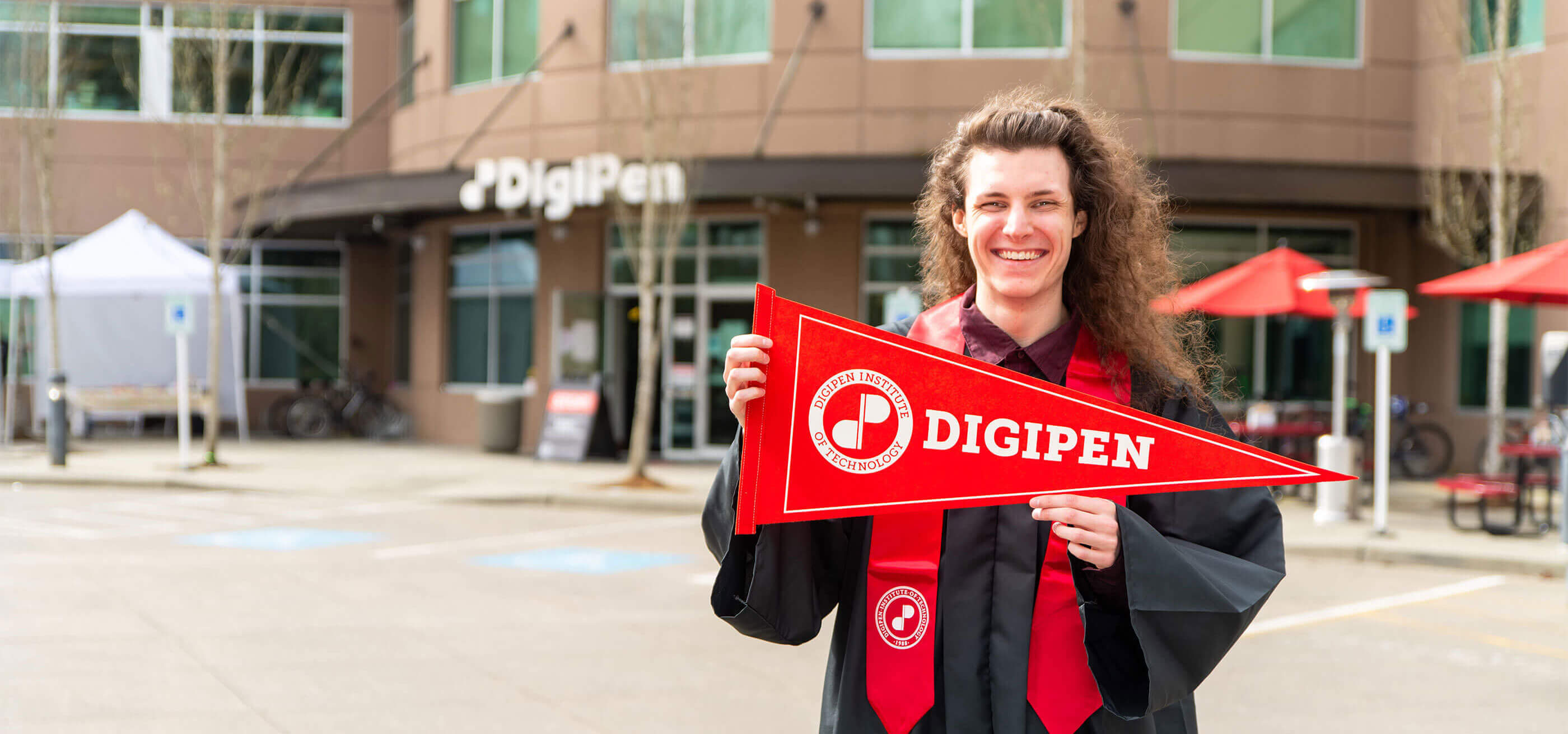 DigiPen graduate Felix Knight DigiPen holding pennant