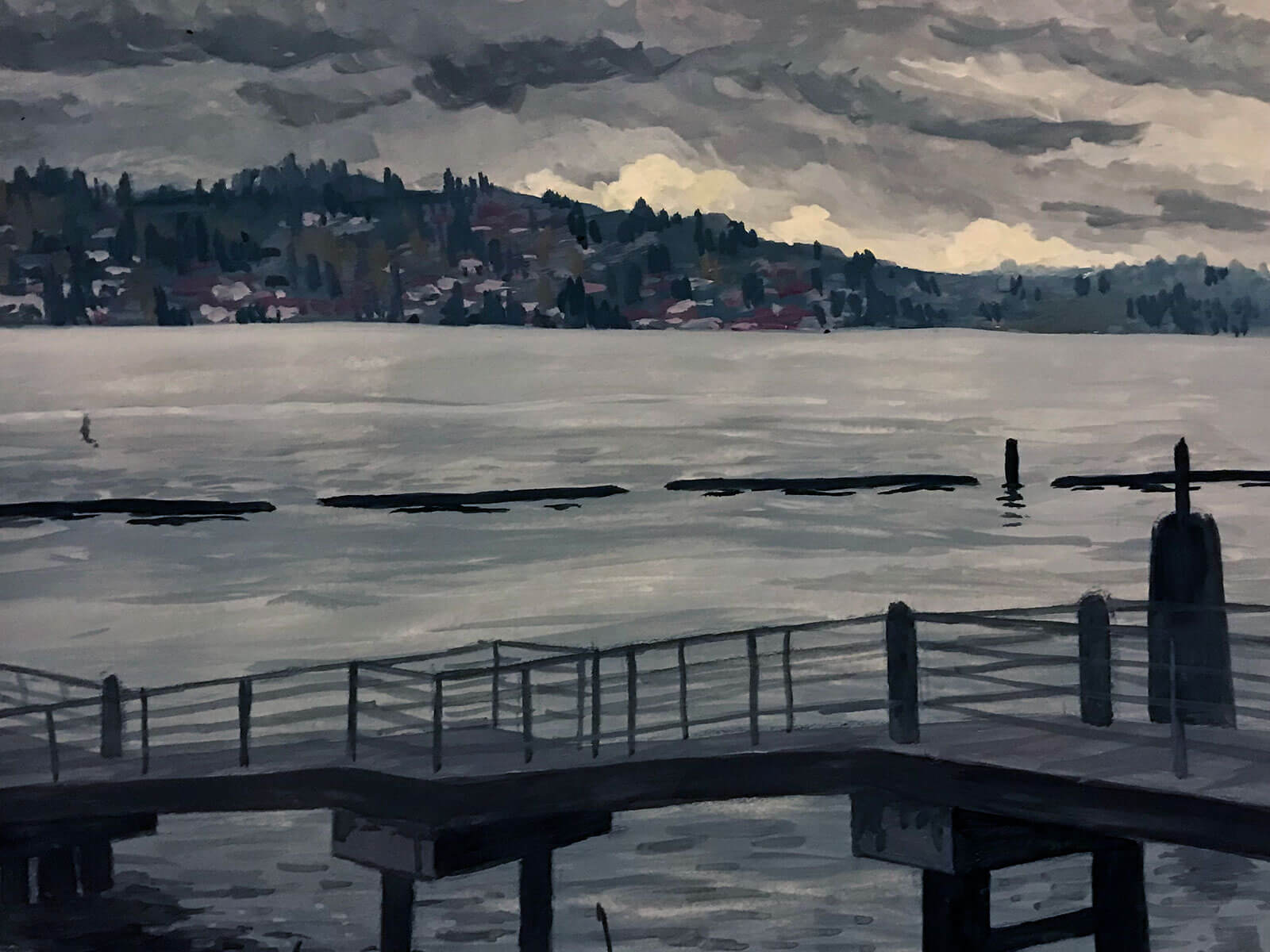View of a dock and lake, houses and stormy gray skies in the distance