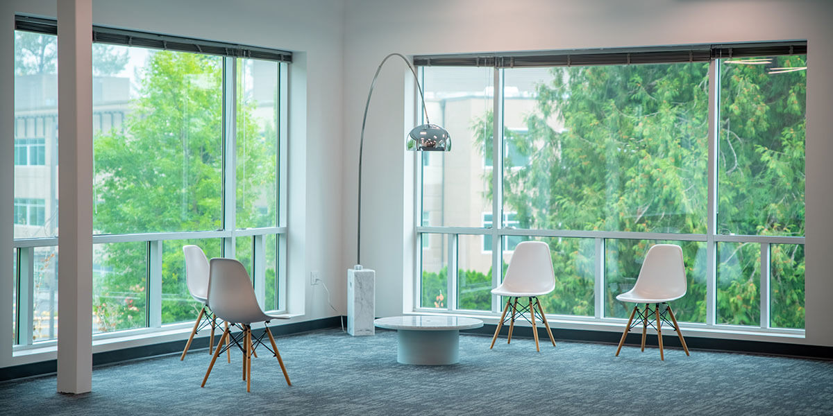Seating area with chairs, a table and lamp in a corner office.