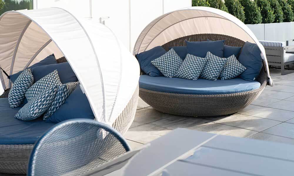 Large covered blue lounge chairs with multiple pillows