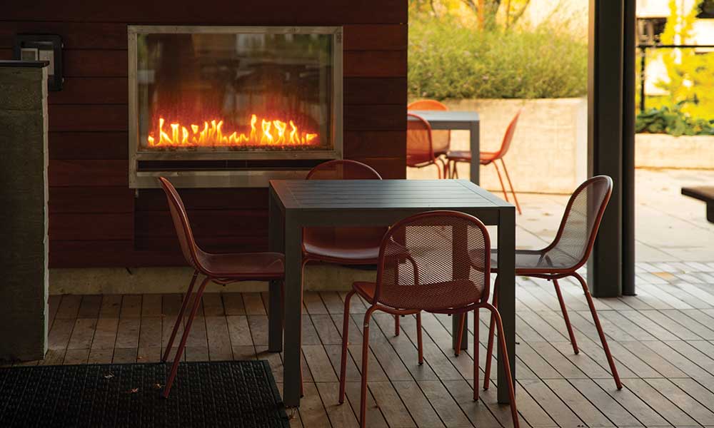 Four chairs sit around a table with a fireplace behind it