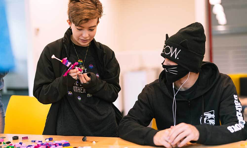 Two students work on a creative crafting activity at a table