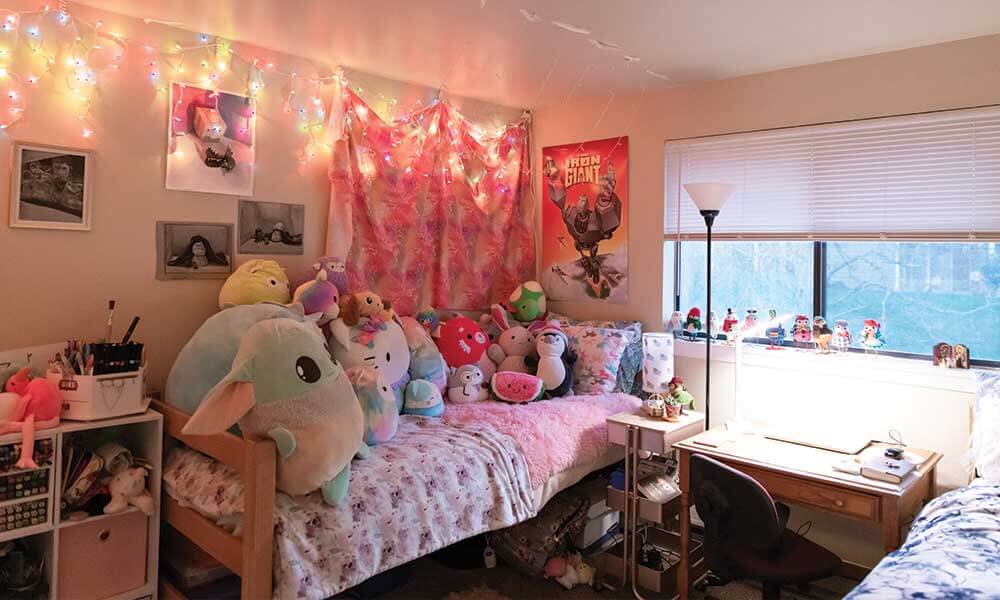A single bed with various stuffed animals and colored lights on the ceiling