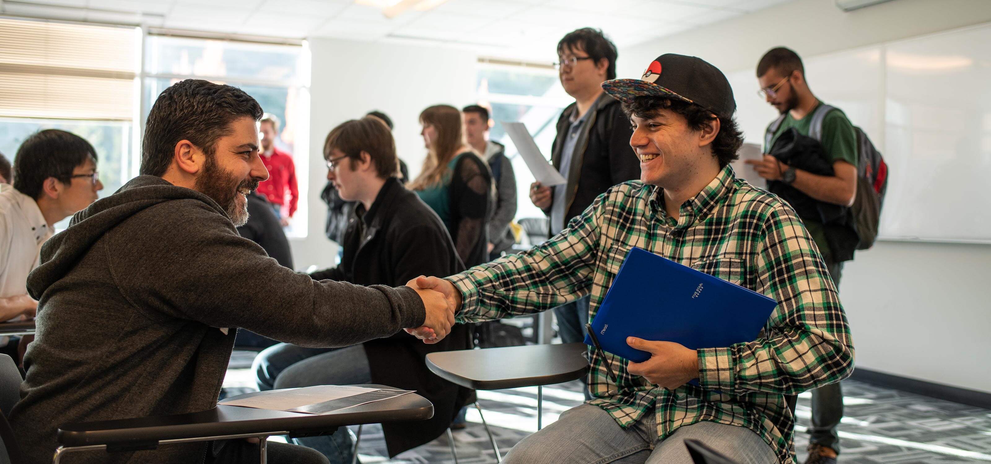 Student smiling and shaking hands with employer