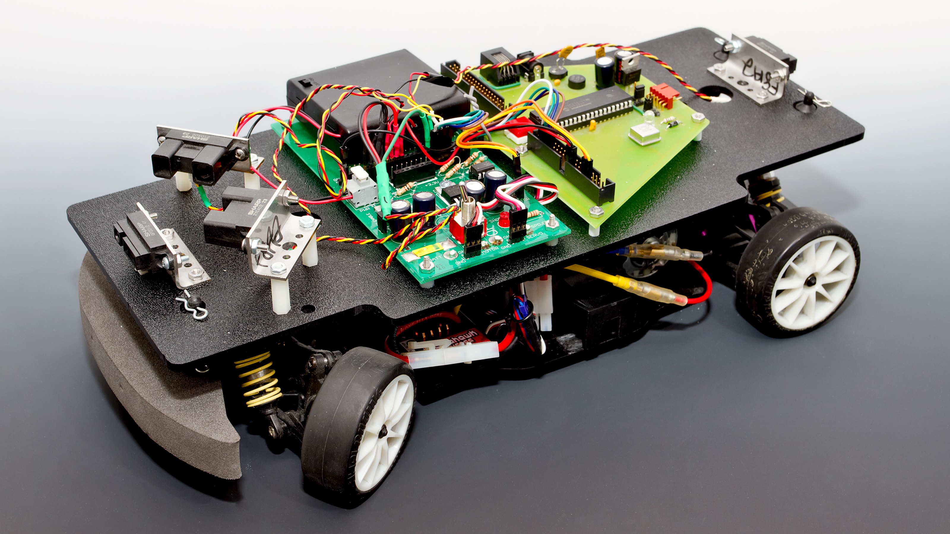 A four wheeled car with infrared sensors and exposed circuitry.