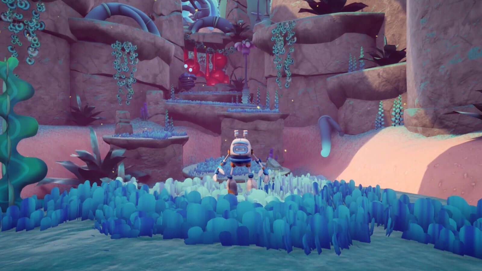 A robot man stands in blue grass, in front of an alien valley filled with vegetation.