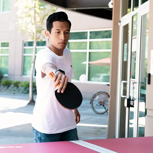 DigiPen student plays on a ping pong table outside.