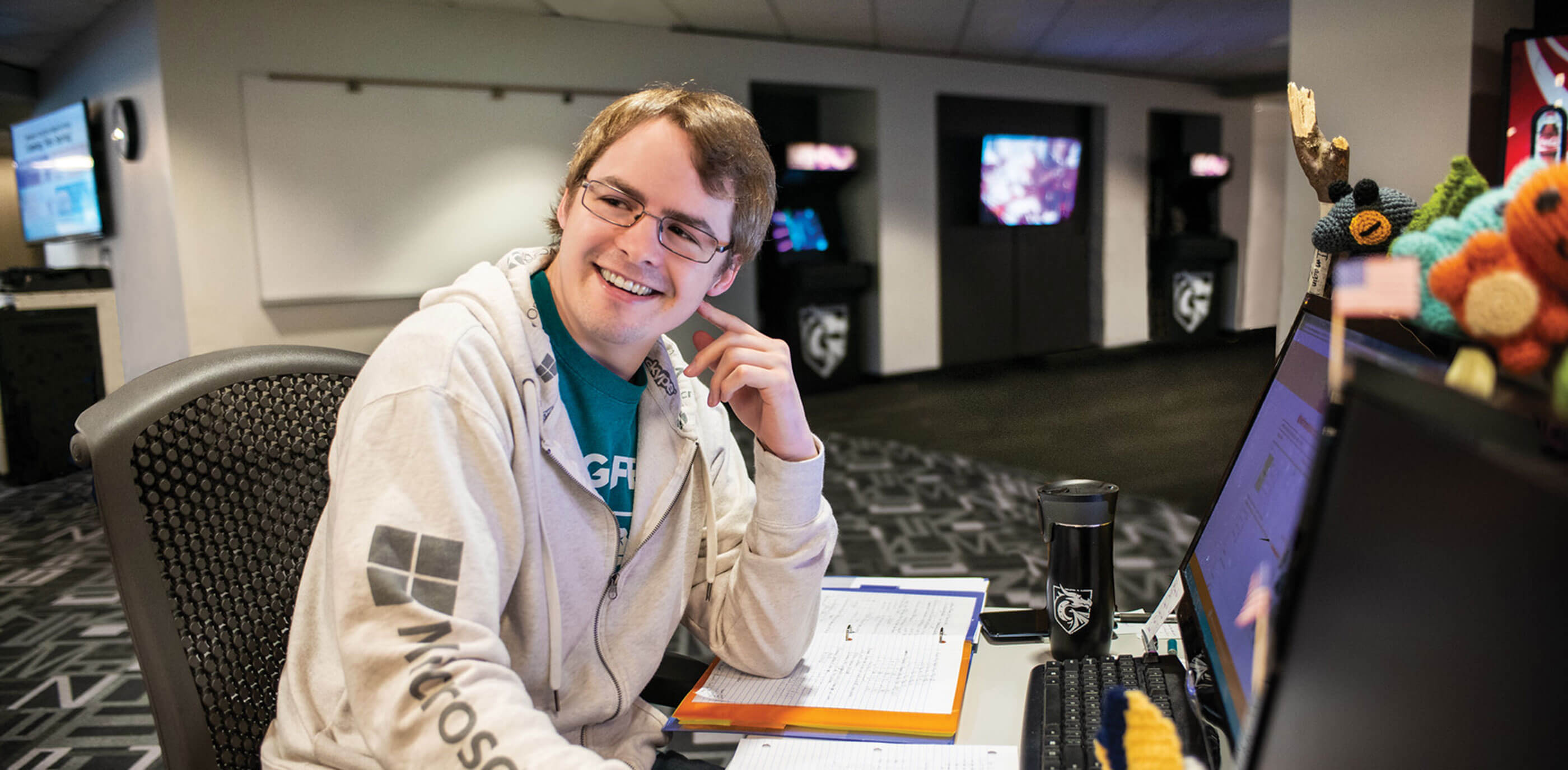 Computer science student sits at desk inside computer lab