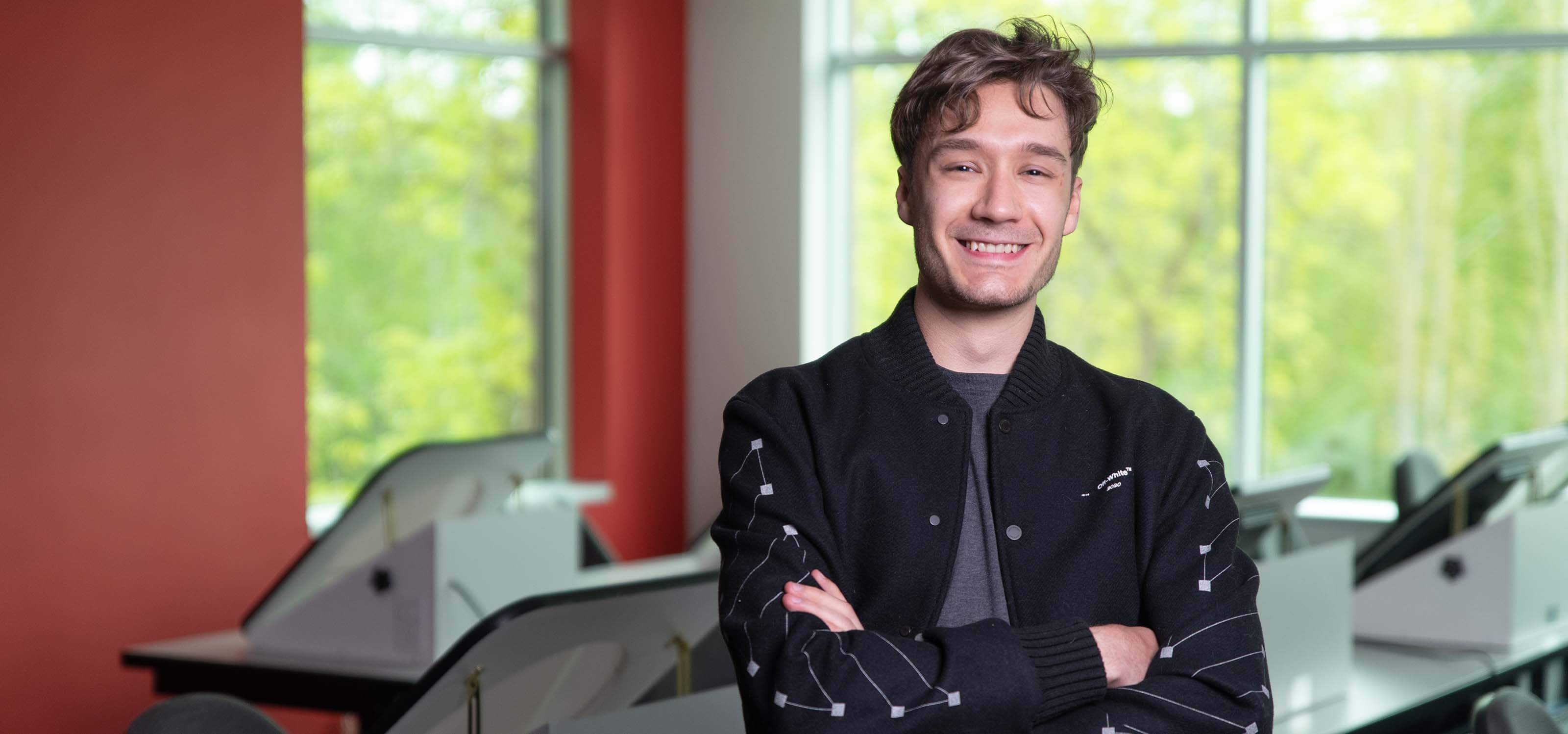 Christophe Bouchard in lecture hall standing with arms crossed wearing a black jacket