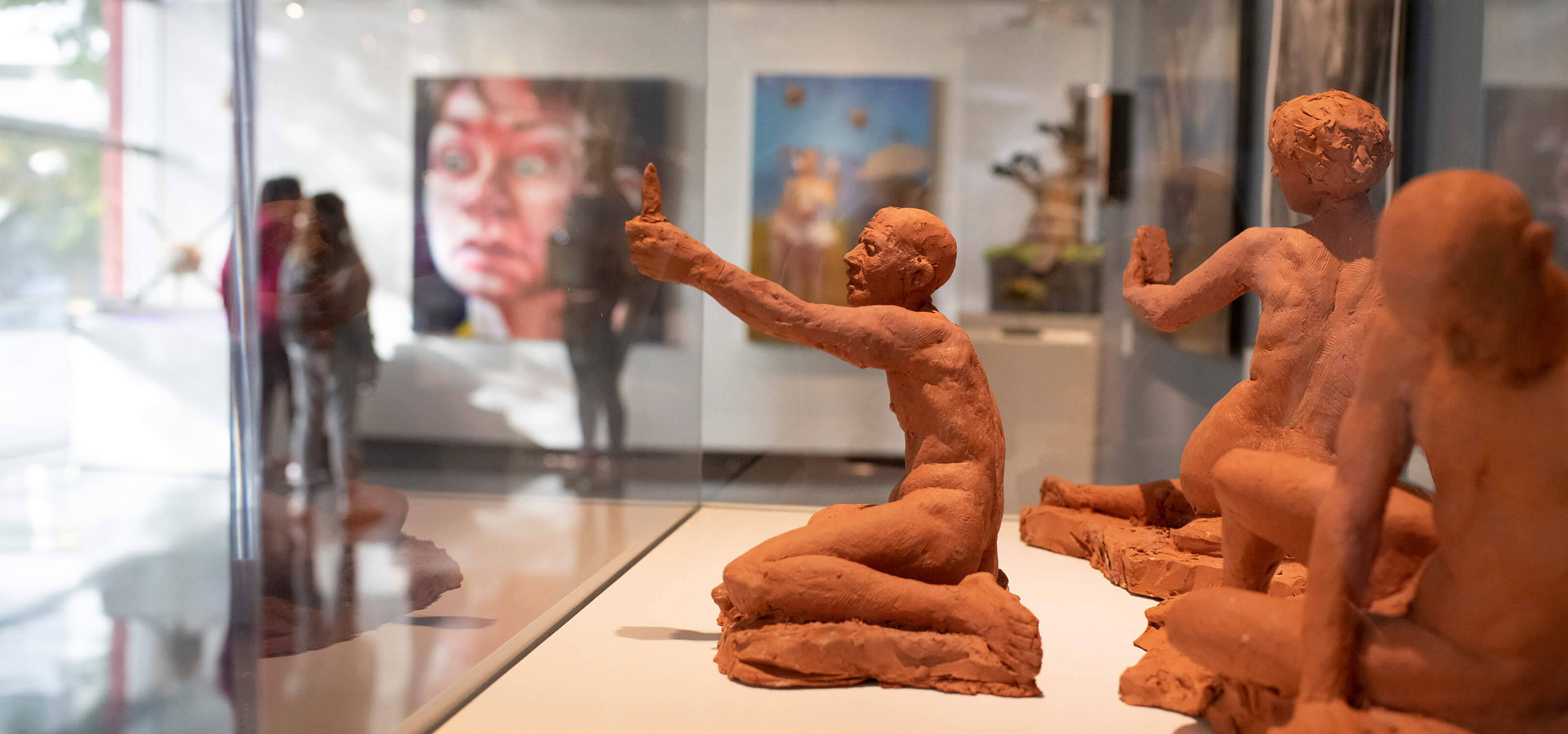 Three terracotta figure sculptures by Alecia Rossano on display at the Bellevue Art Museum.