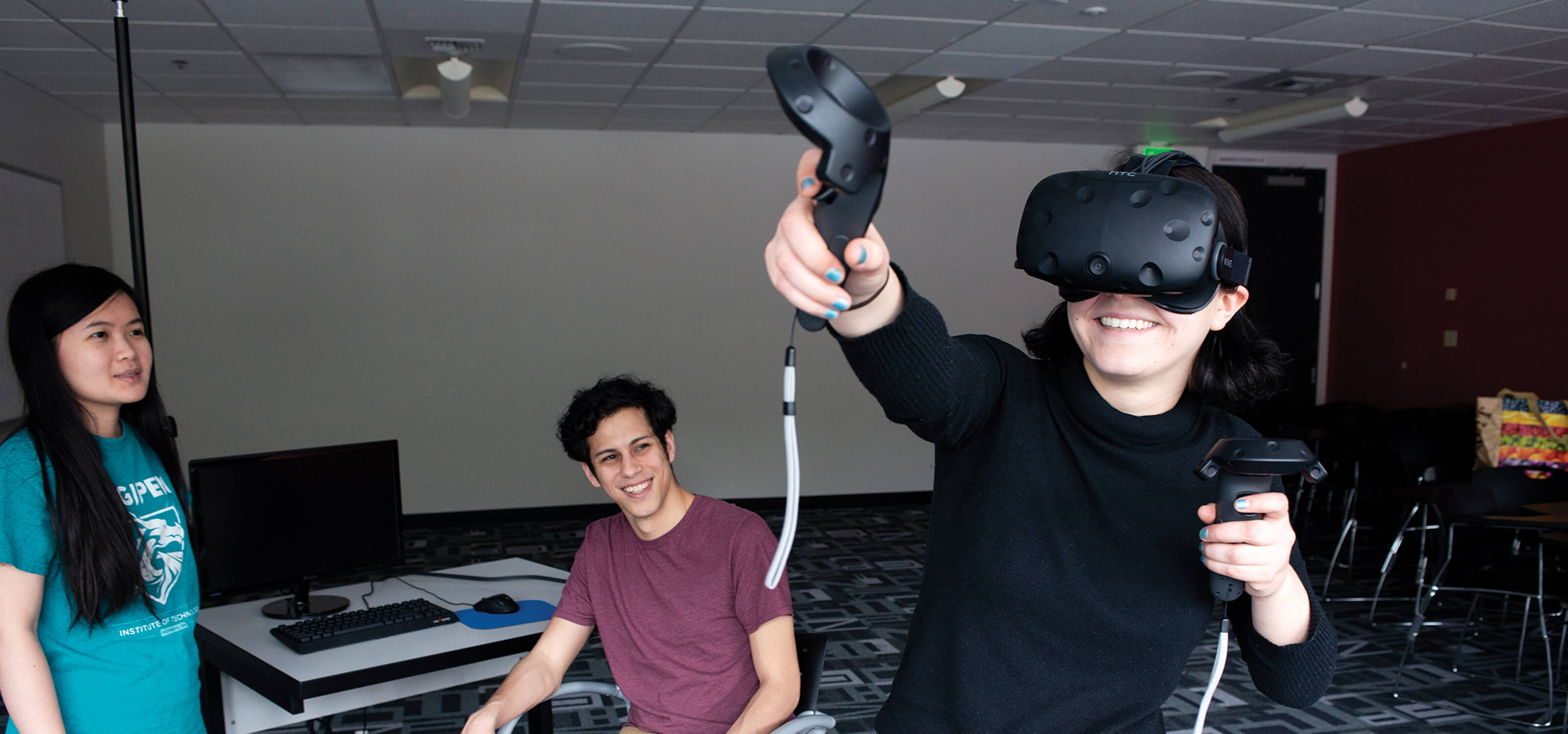A DigiPen student tries out their VR game team project as their teammates smile at them.