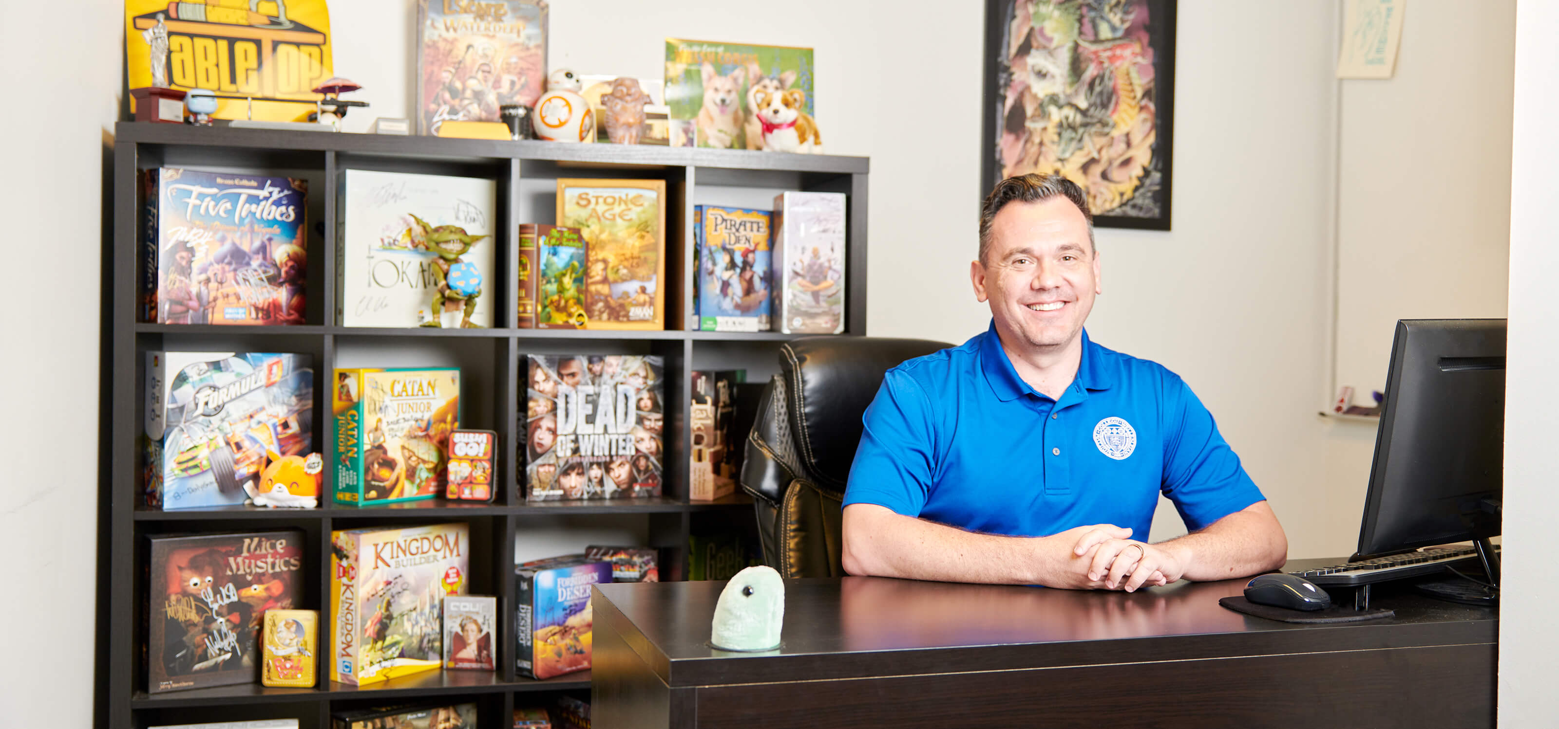 Senior game design lecturer Boyan Radakovich smiles in his office full of tabletop games.
