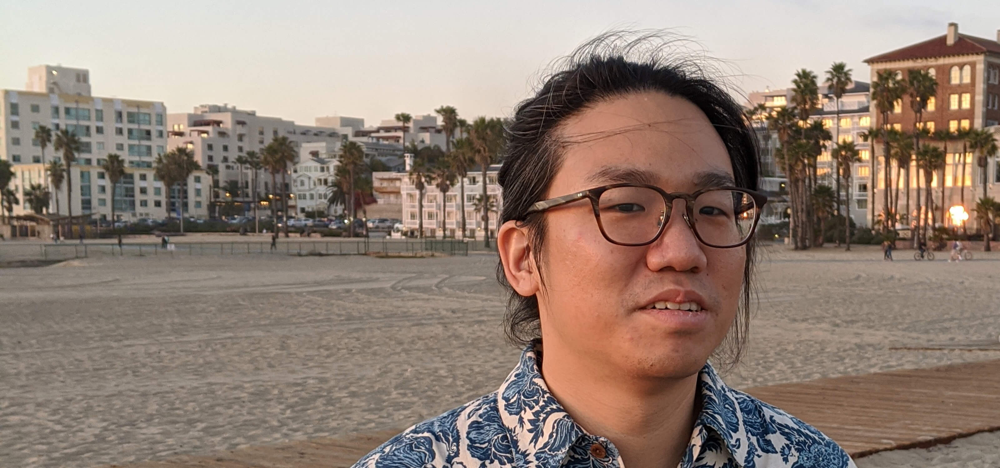 DigiPen graduate Chia-Hao Ching poses on a beach lined with palm trees.