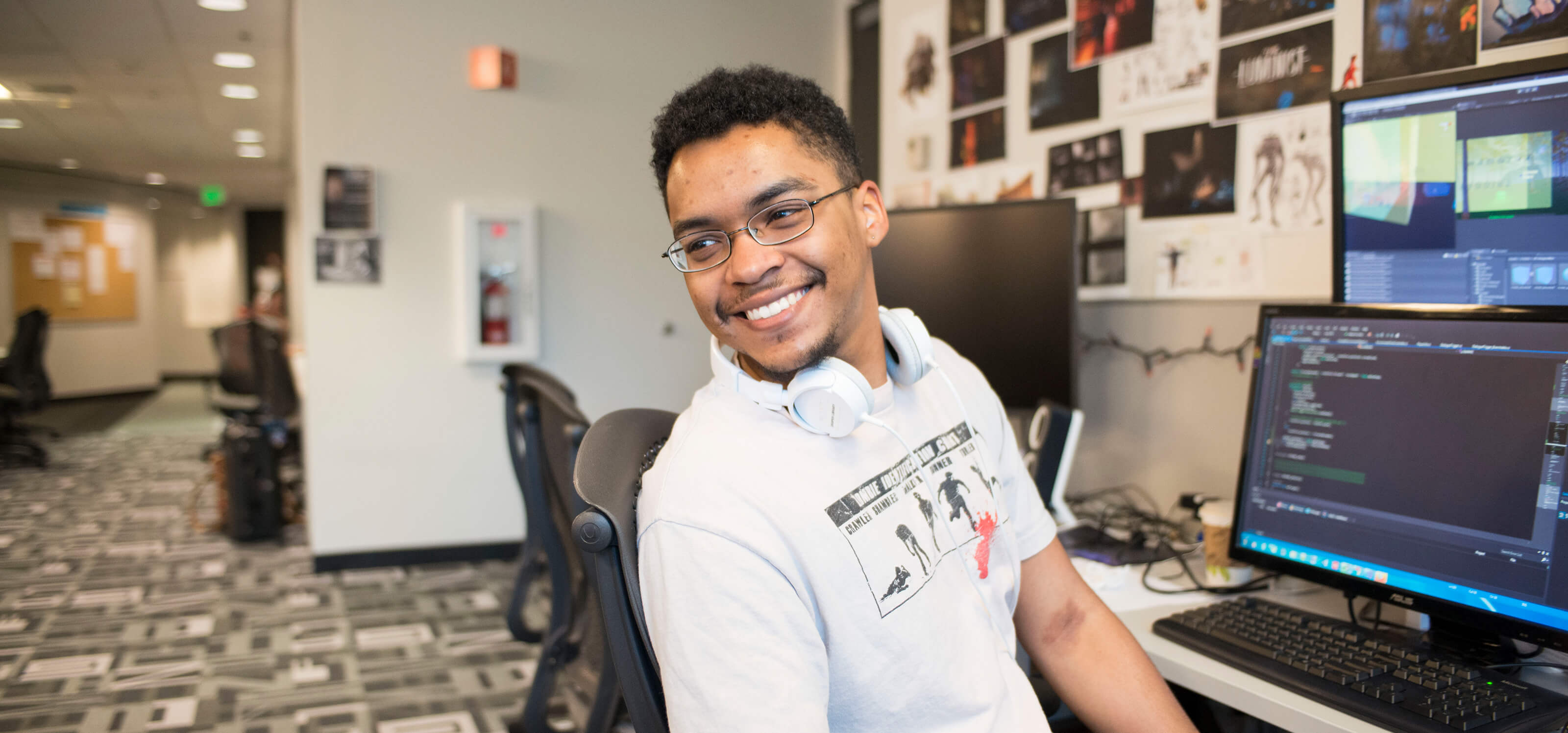 A DigiPen student smiling as he leans away from a computer screen