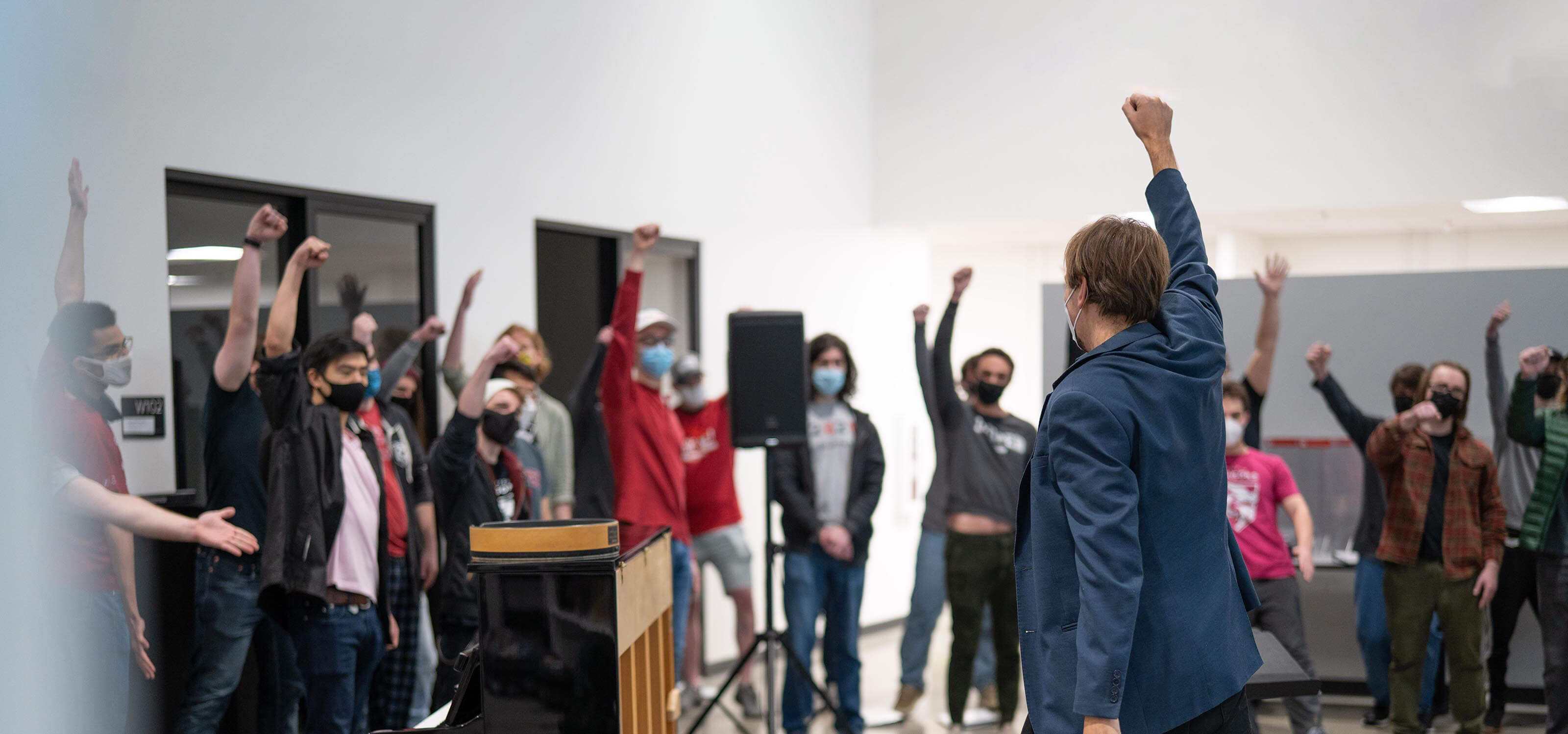 The DigiPen Dragon Chorus raises their fists in celebration in The Wing.