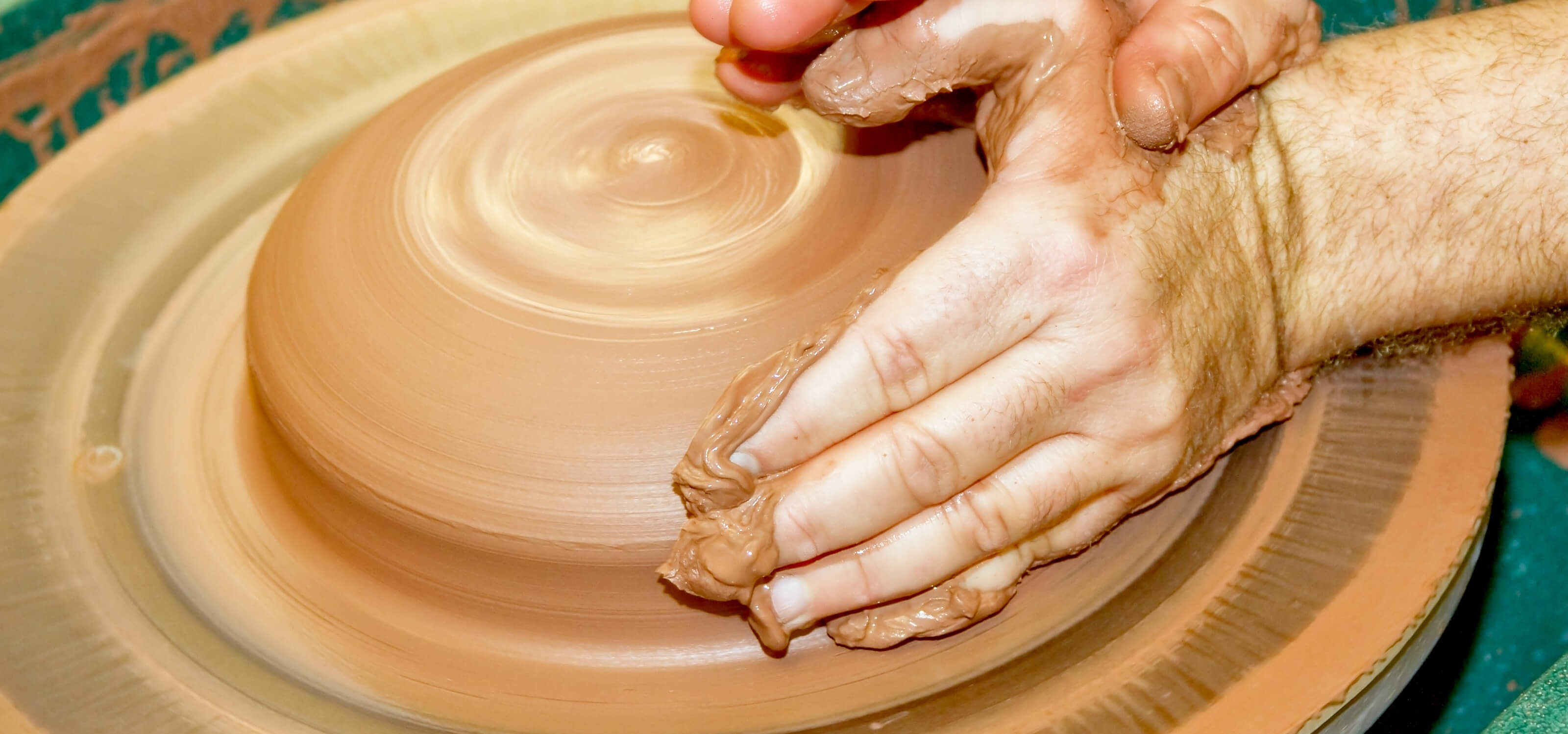 Hands molding clay on a spinning wheel in the new DigiPen ceramics studio