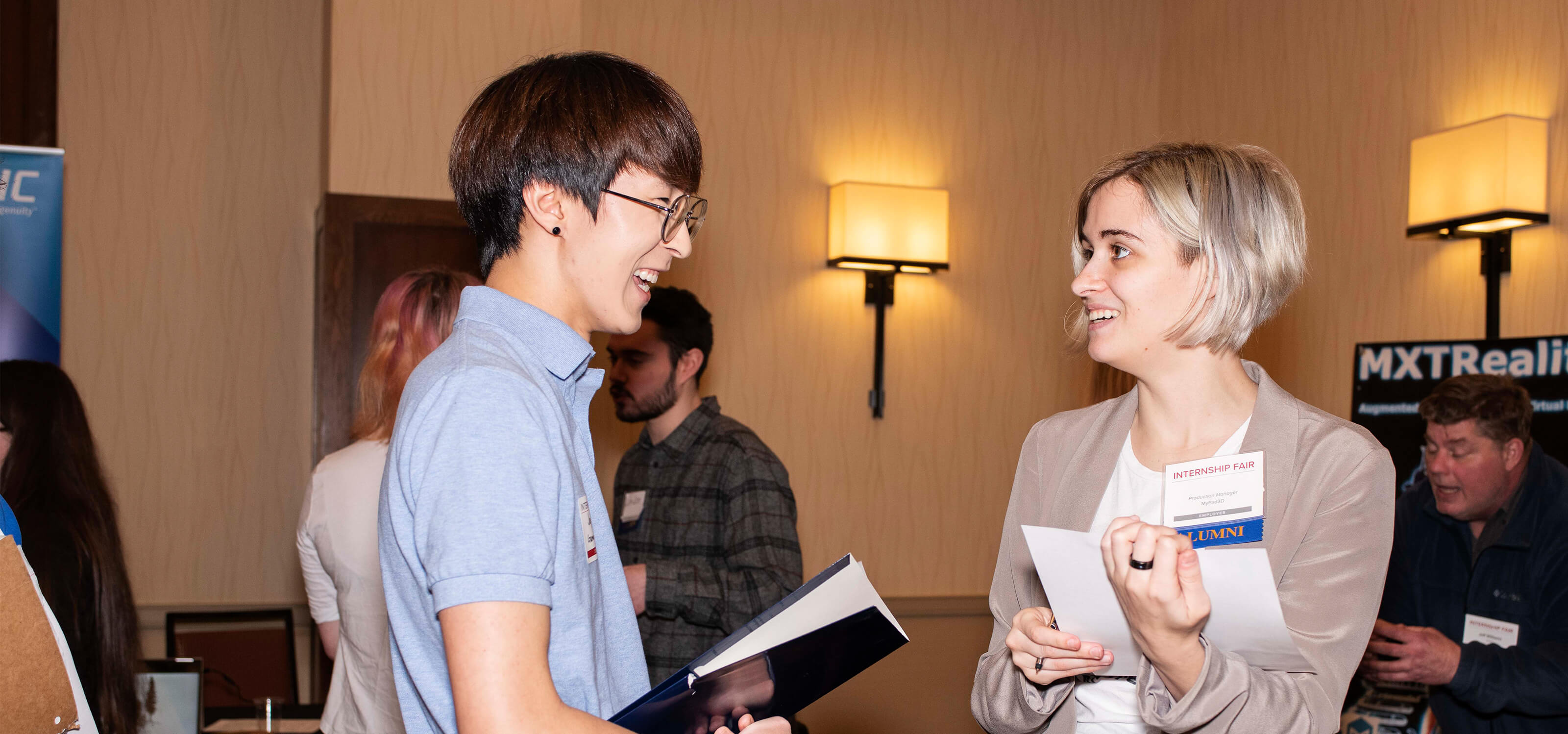 A company representative with an alumni tag chats with a current student at the 2019 Internship Fair.