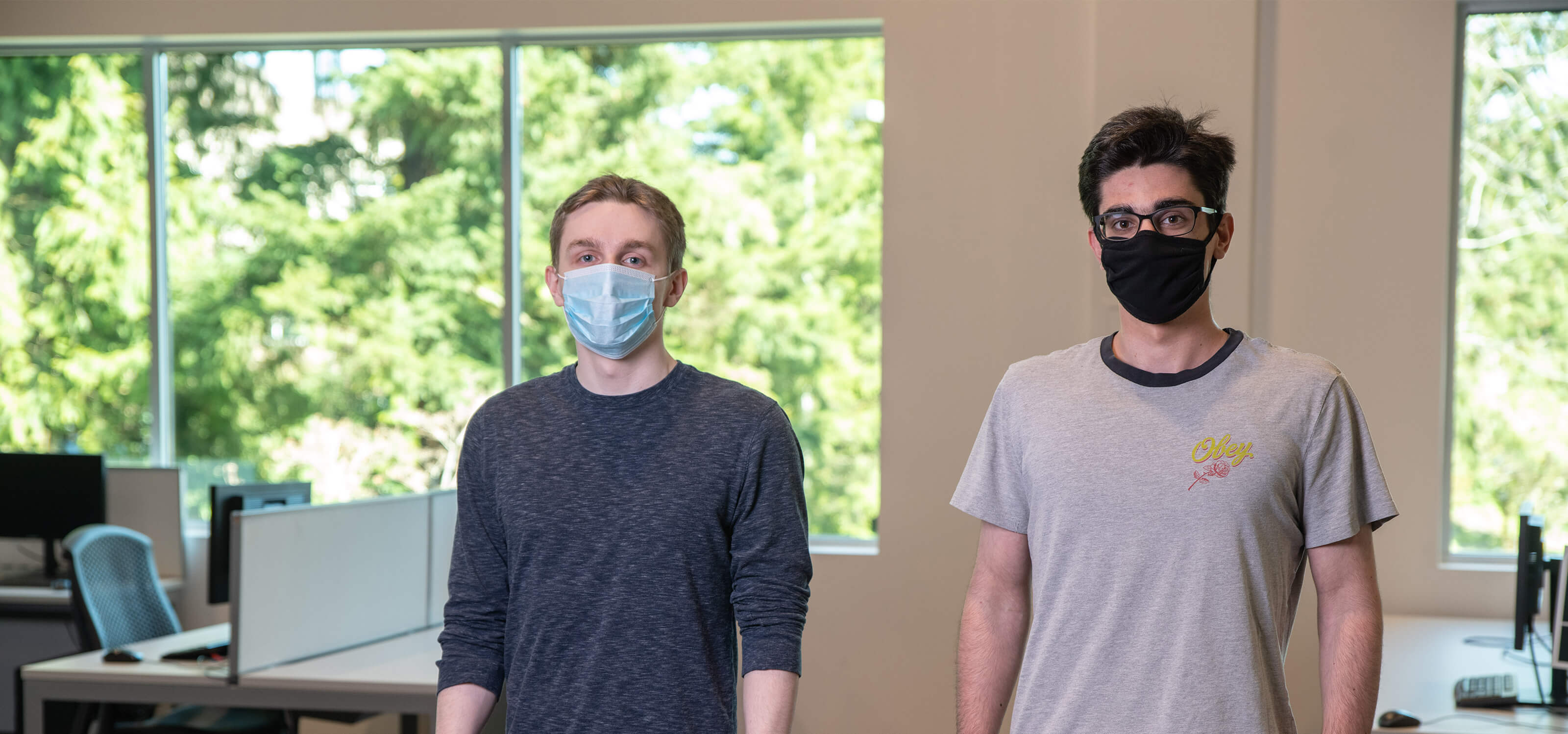 DigiPen BS in Computer Science in Machine Learning sophomores Eric Zander and Andrew Ardeleanu pose in a campus computer lab wearing face masks. 