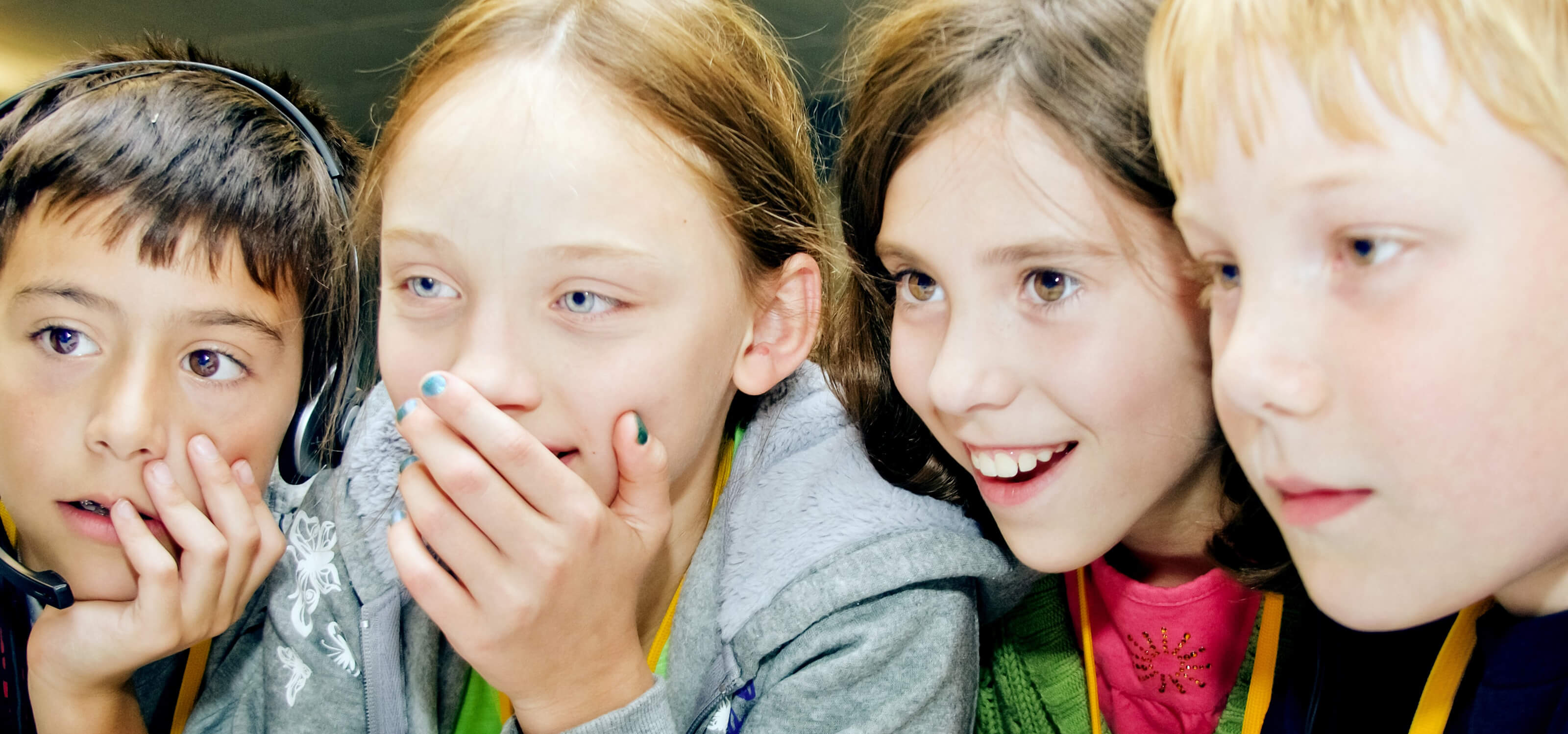 Four young ProjectFun students smiling at a computer monitor
