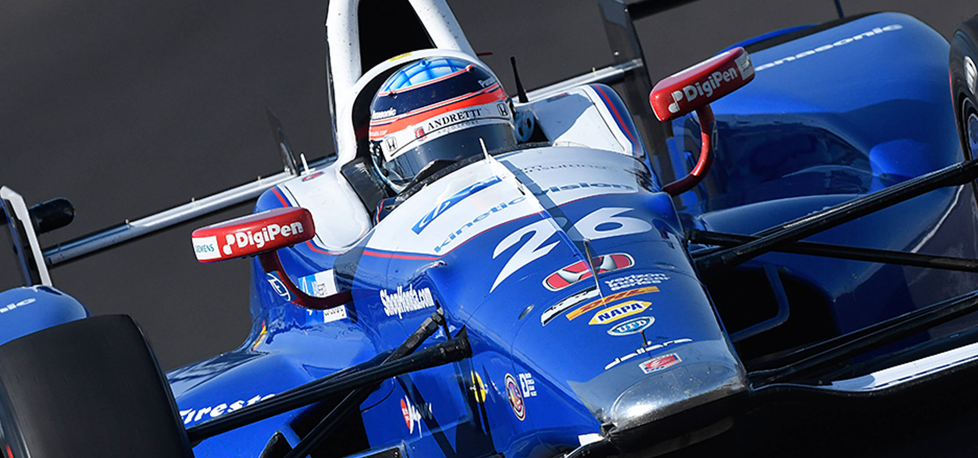 Takumo Sato driving an Indy car featuring the DigiPen logo