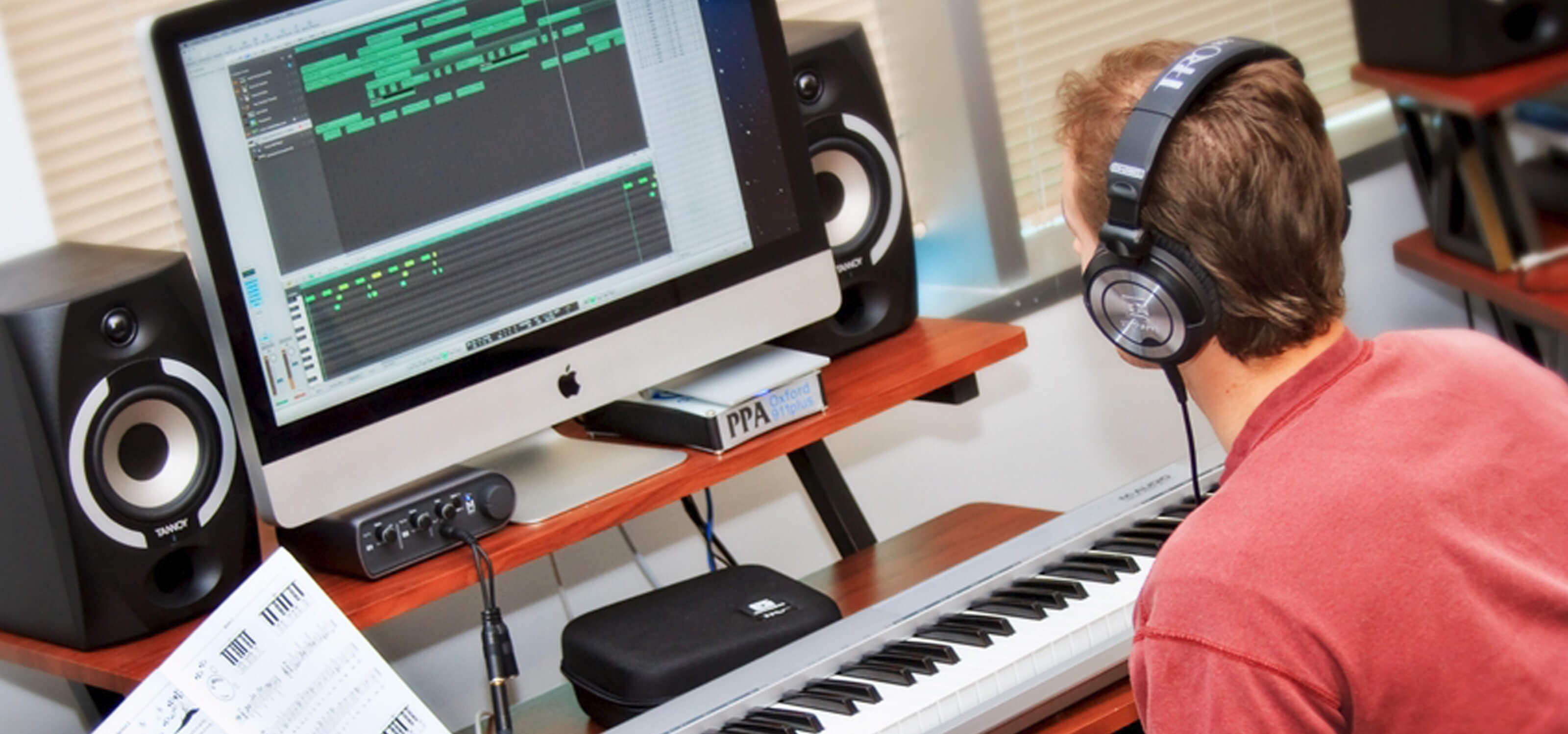DigiPen sound design student composing music with a computer and a digital piano keyboard