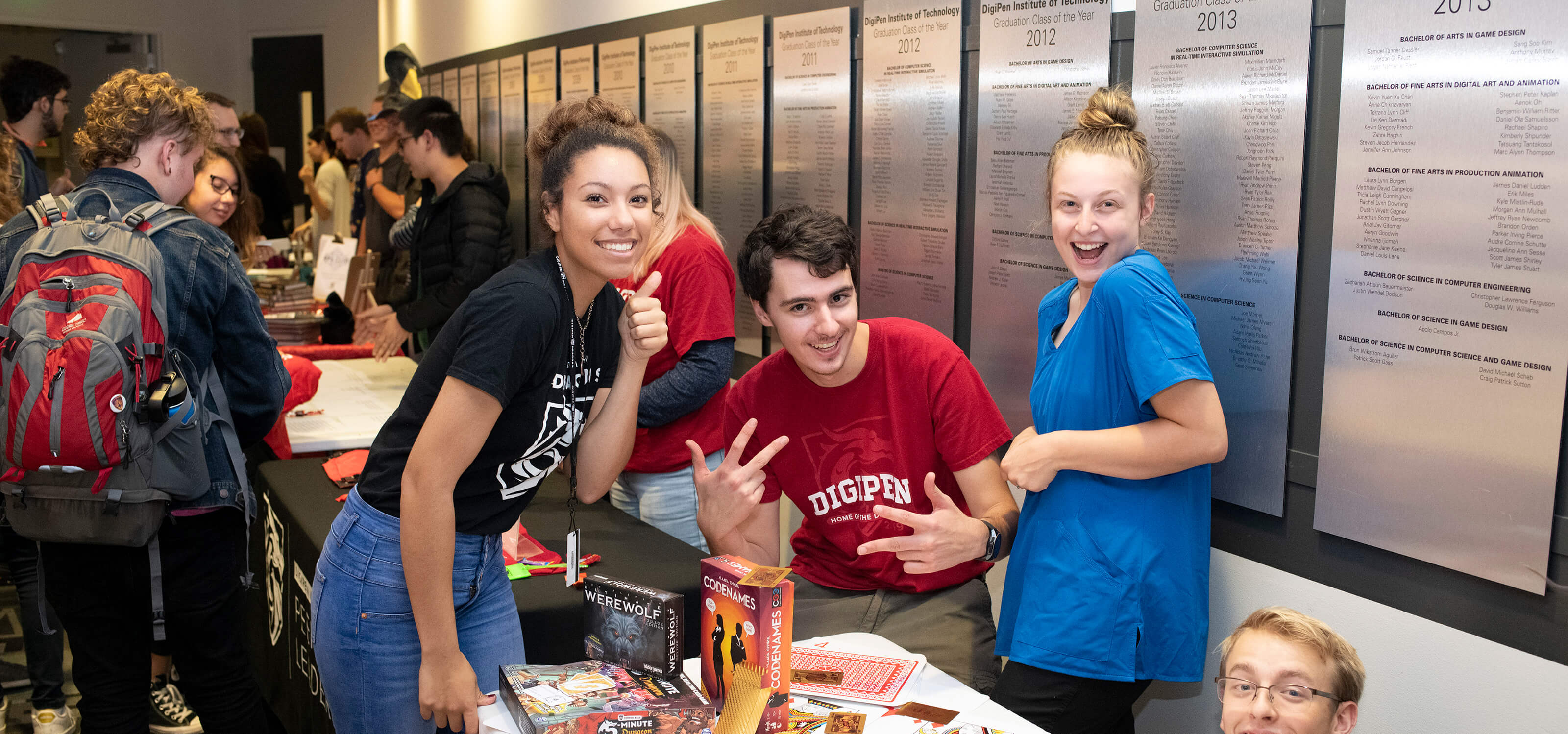 Students smile and pose around a table of board games.