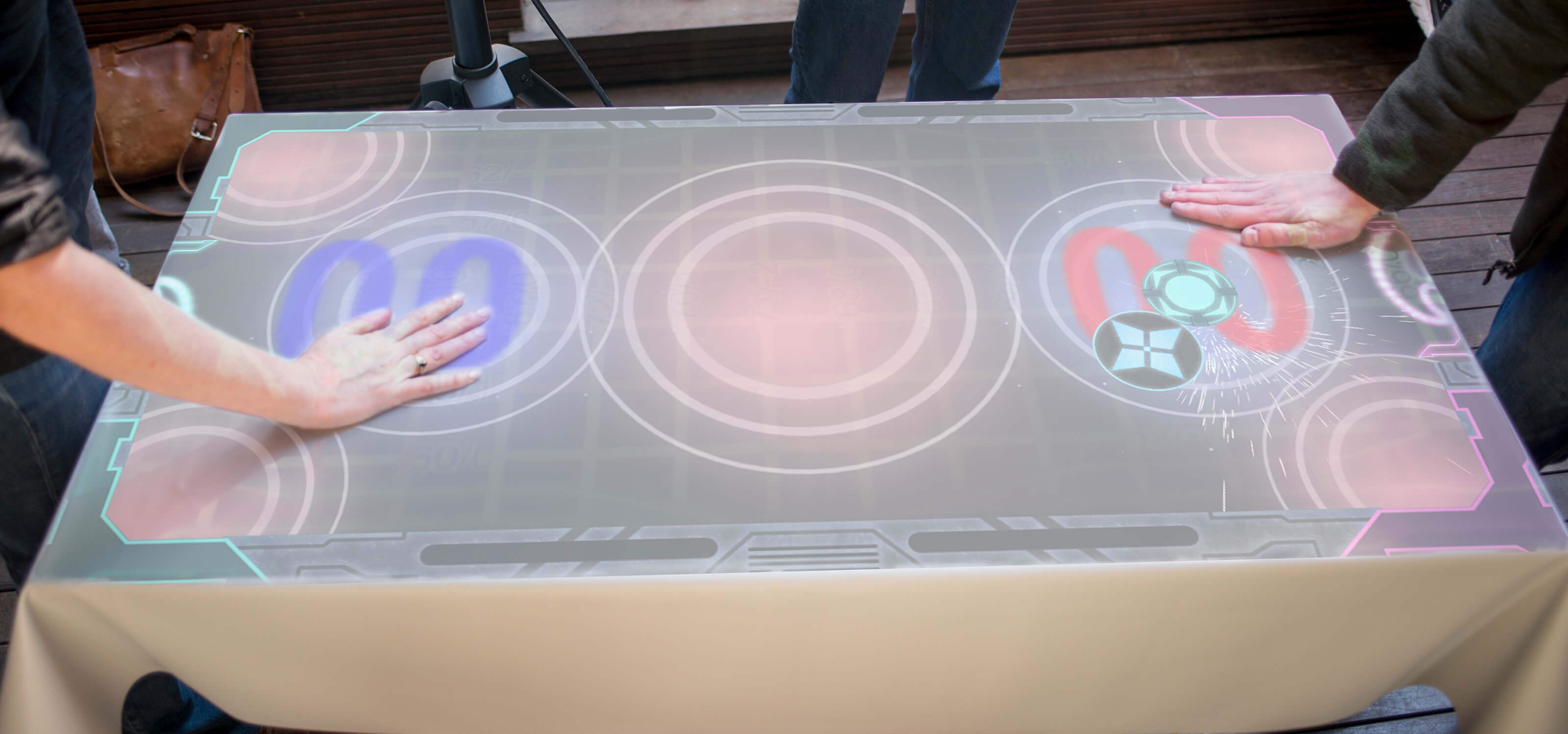 Overhead view of two people playing Striker Air Hockey with only their hands